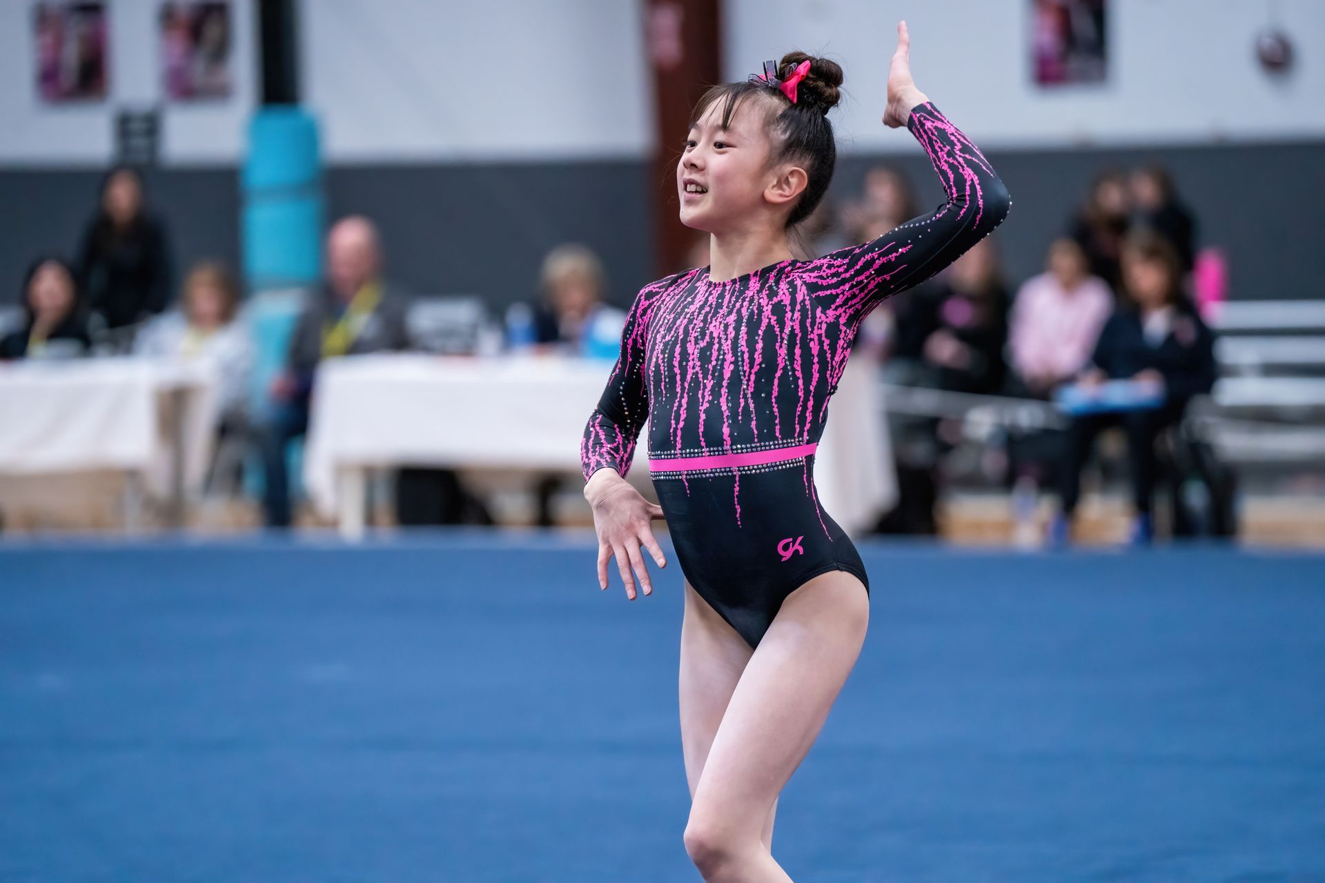 A young girl is doing a routine on a balance beam in a gym.
