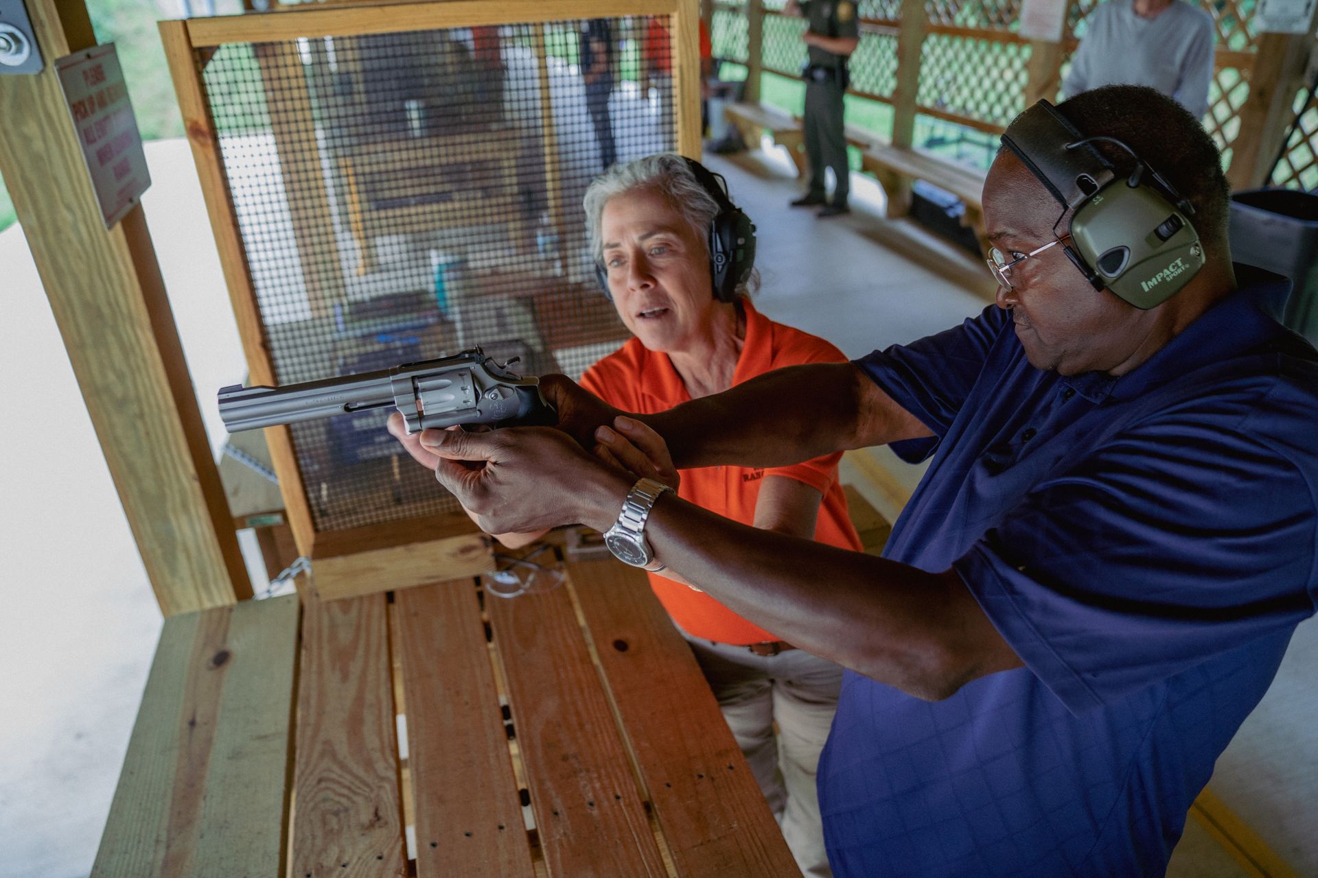 Man at a shooting range shooting with the help of an older woman