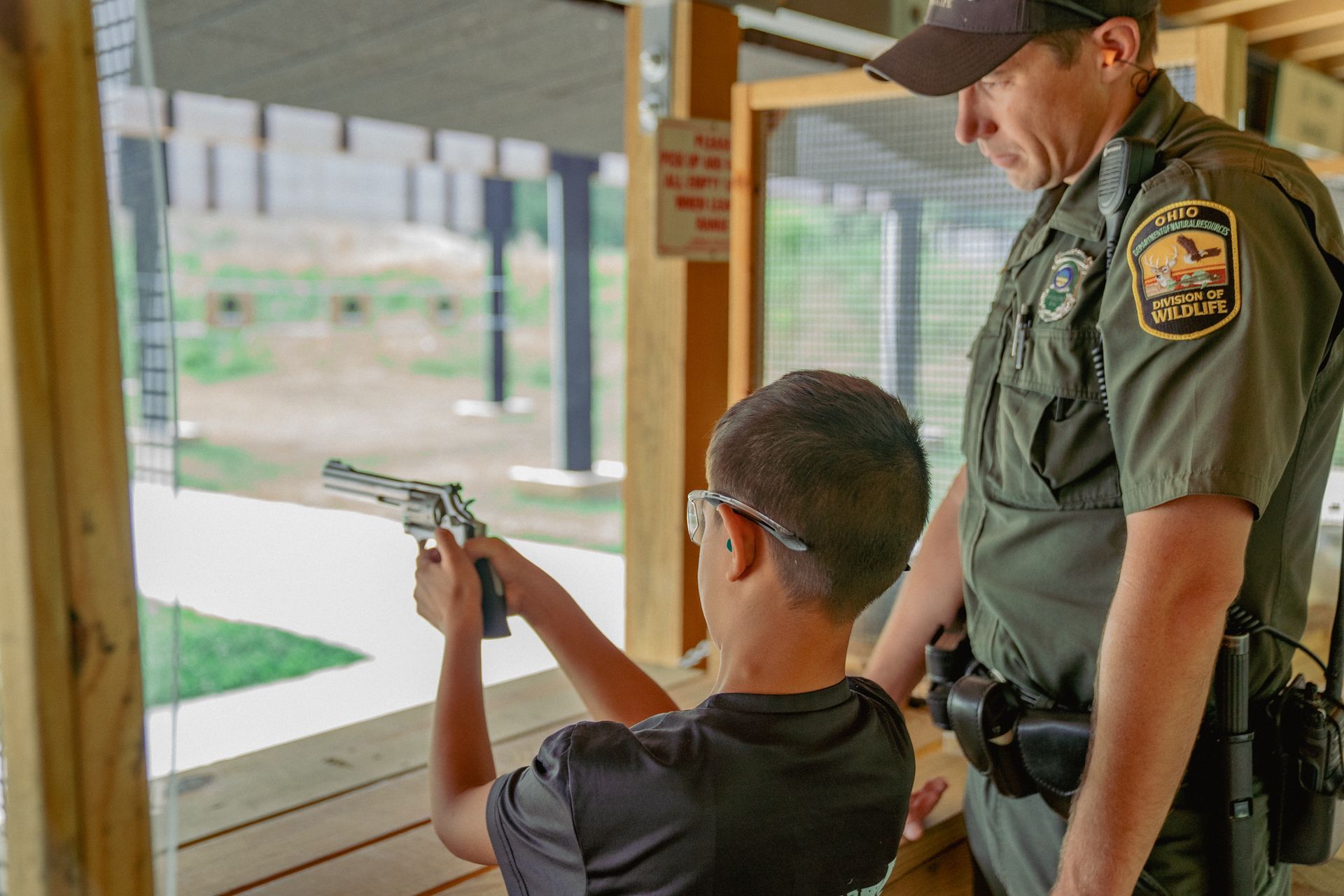 Young boying learning to shoot a gun from a park ranger
