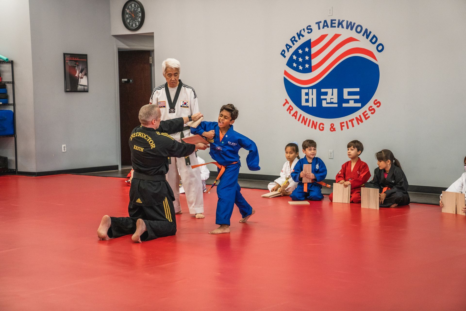 A group of children are practicing taekwondo in a gym.