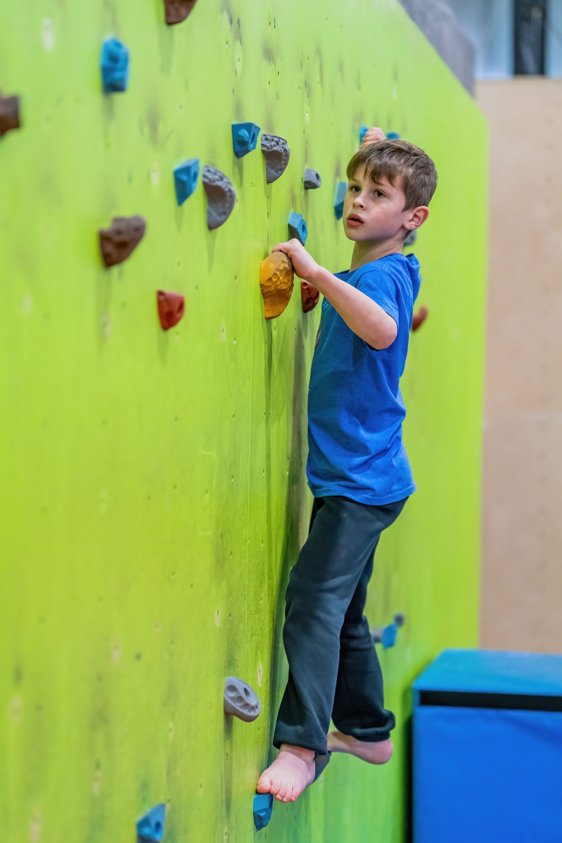 A young boy is climbing a climbing wall.