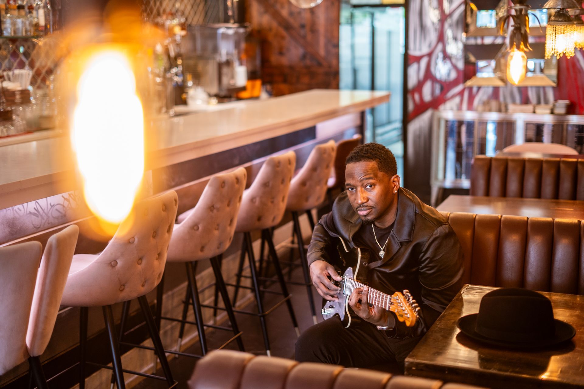 A man is sitting at a table playing a guitar in a restaurant.