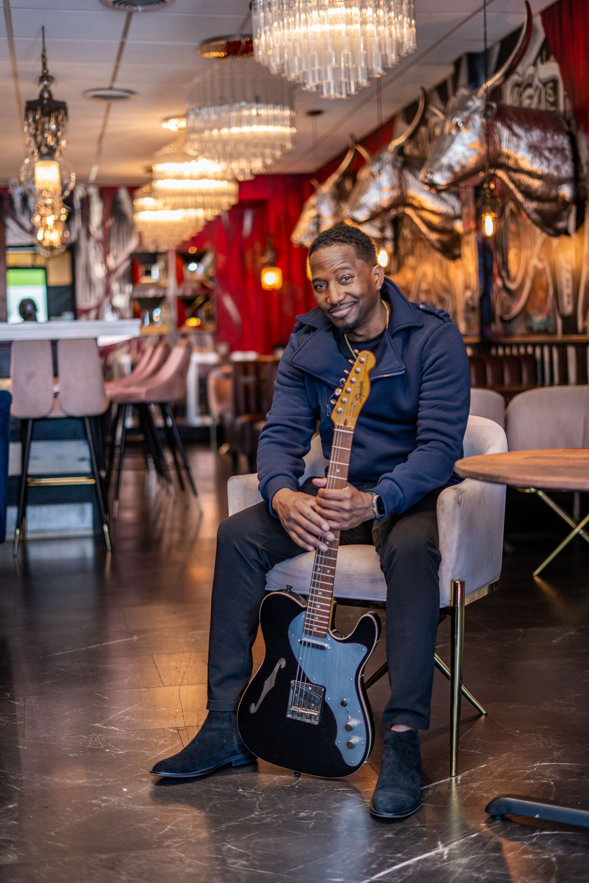 A man is sitting in a chair holding an electric guitar.