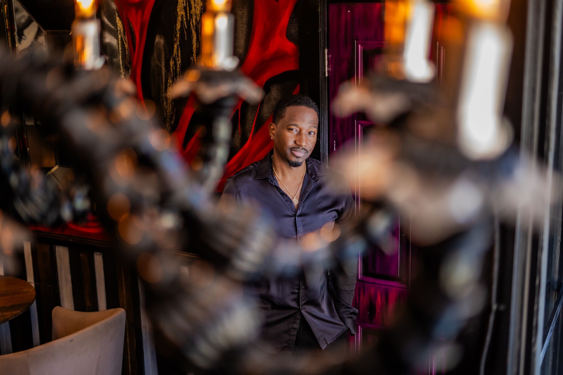 A man is standing in front of a chandelier in a room.