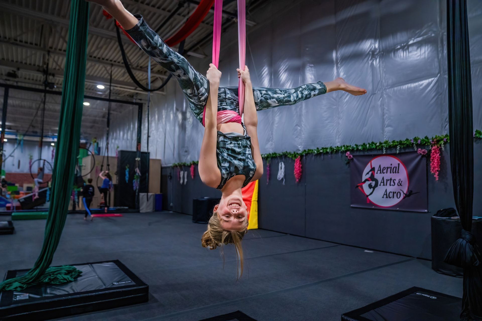 A woman is doing aerial acrobatics in a gym.