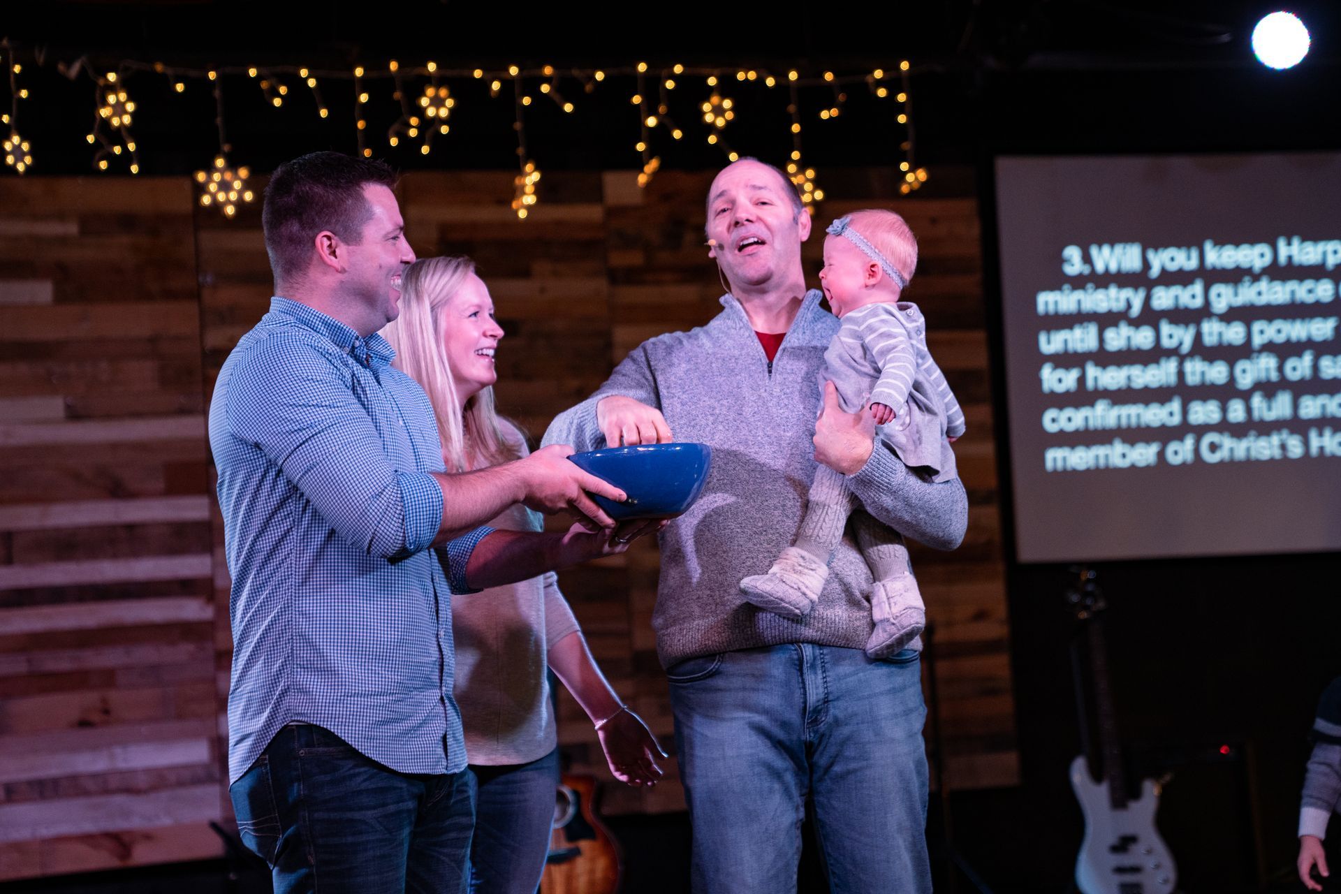 A man is holding a baby while a woman holds a bowl.