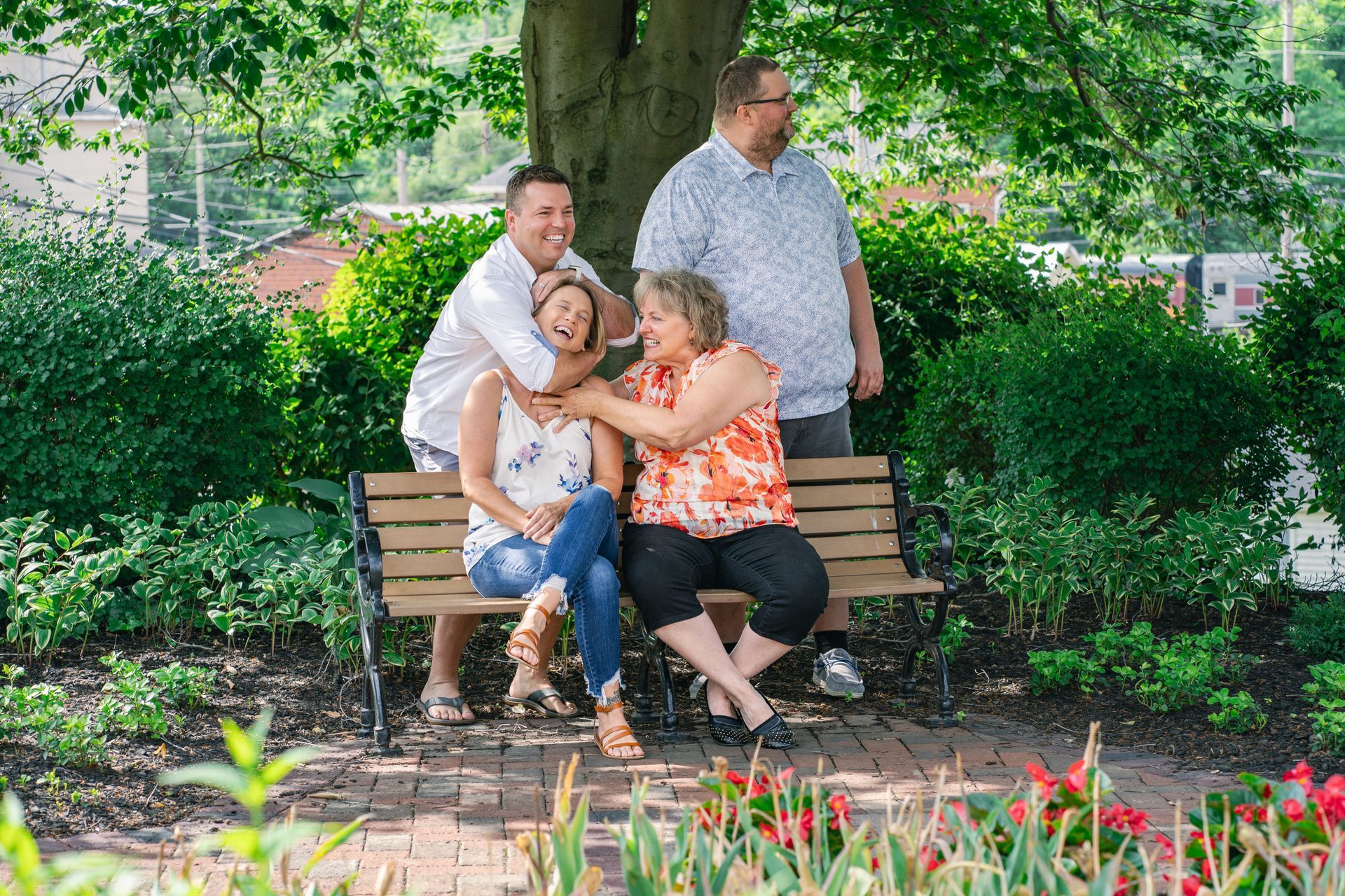 A family is sitting on a park bench under a tree.
