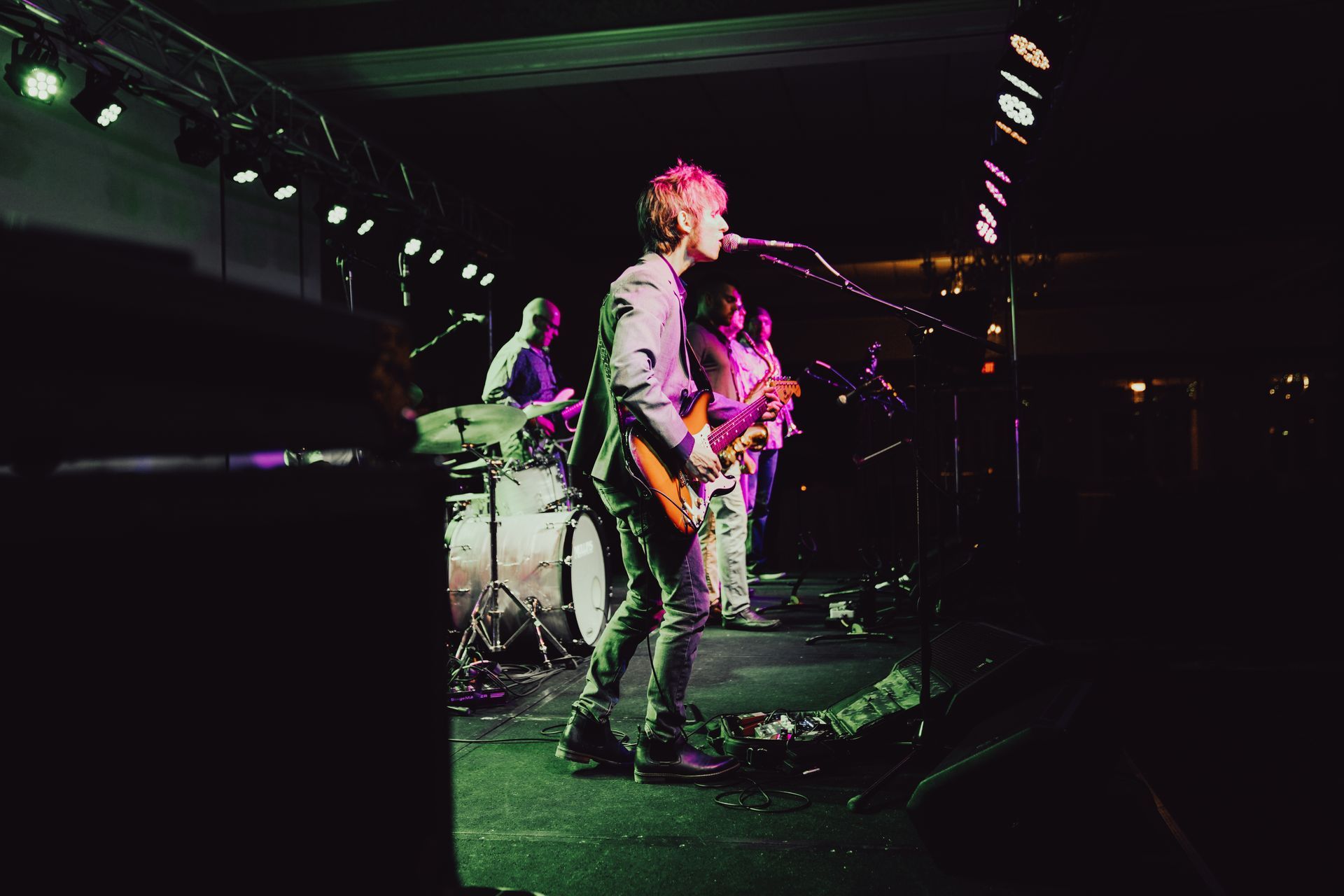 A man is playing a guitar and singing into a microphone on a stage.