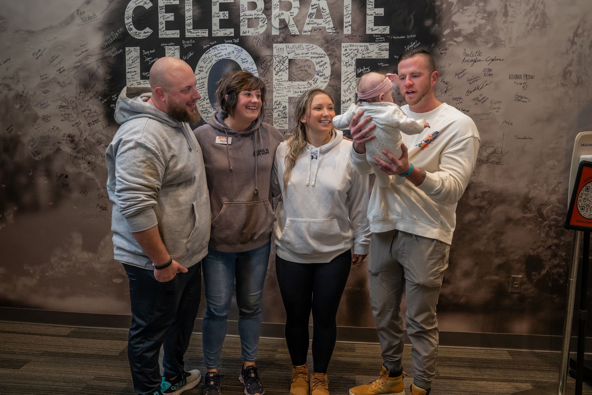 A group of people are posing for a picture in front of a wall that says `` celebrate hope ''.