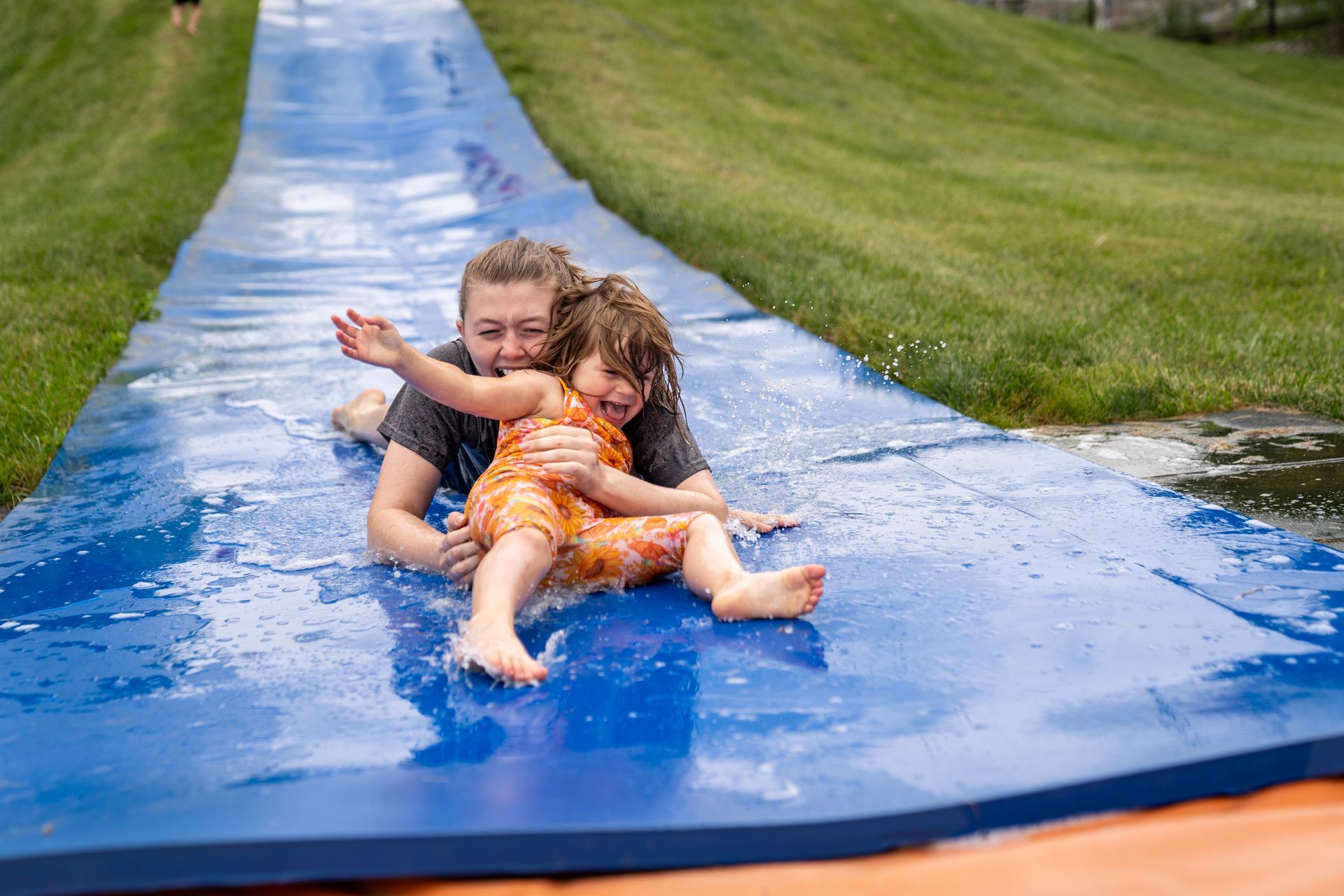 A woman and a little girl are riding down a water slide.