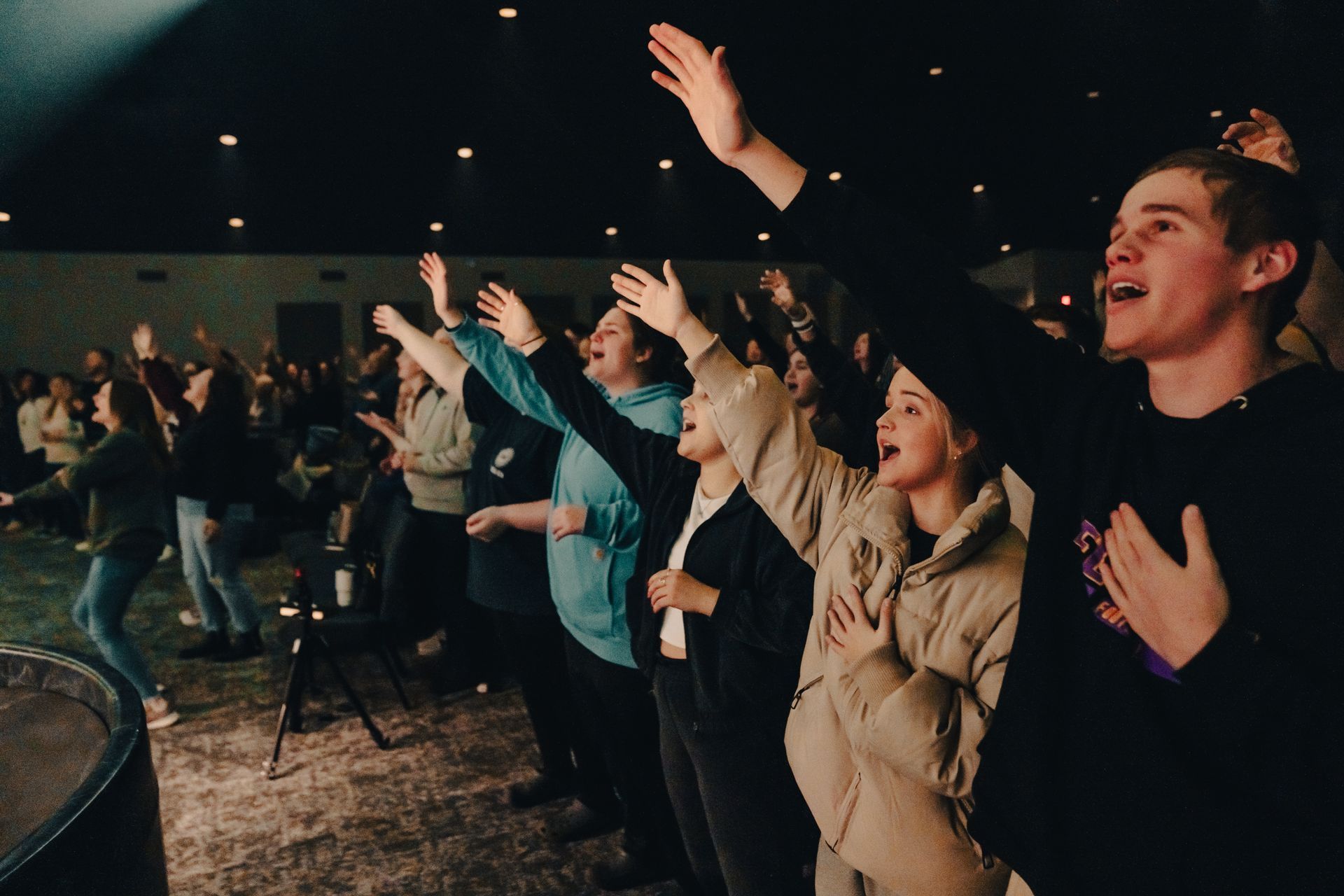A group of people are standing in a room with their hands in the air.