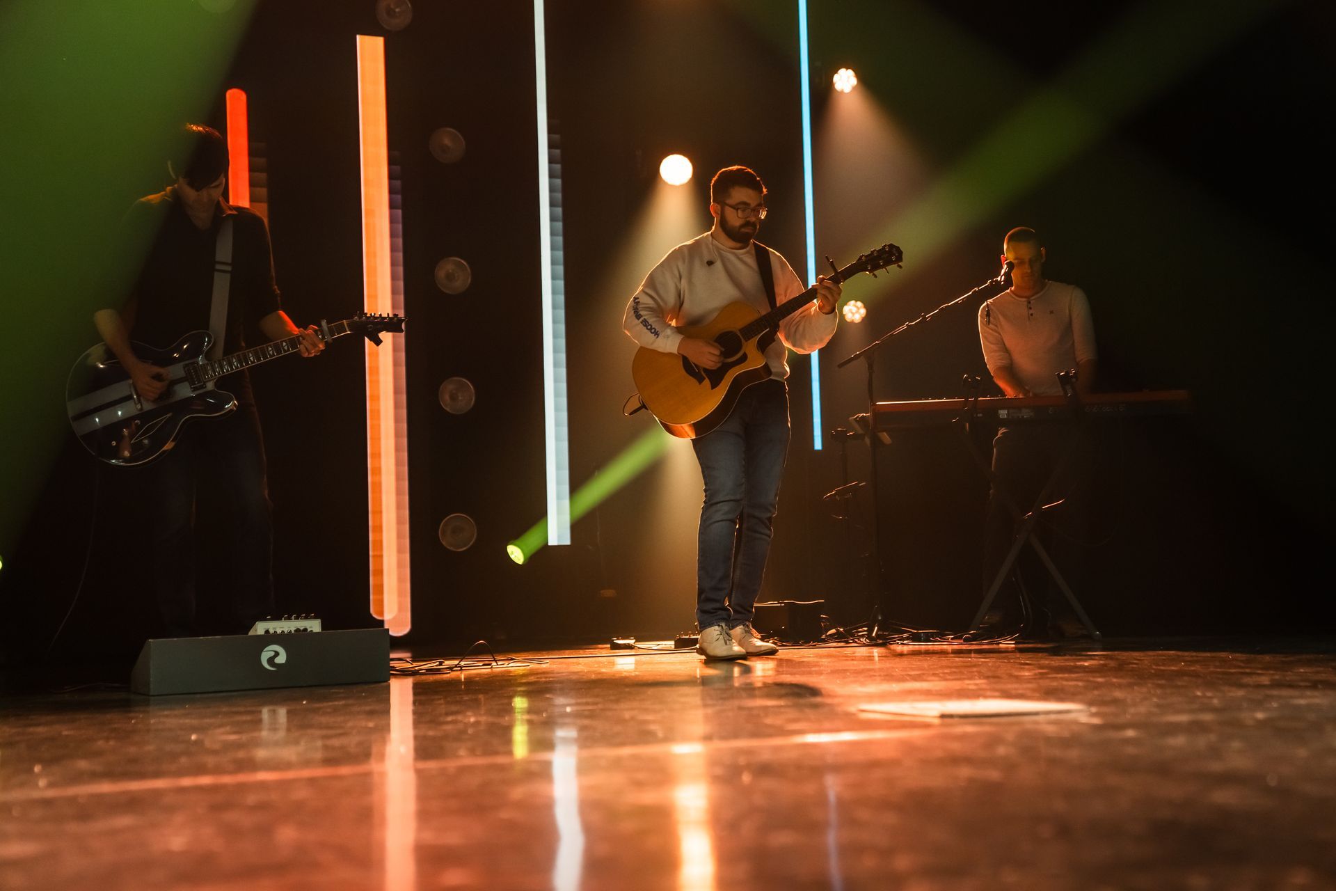 A man is playing a guitar on a stage in a dark room.