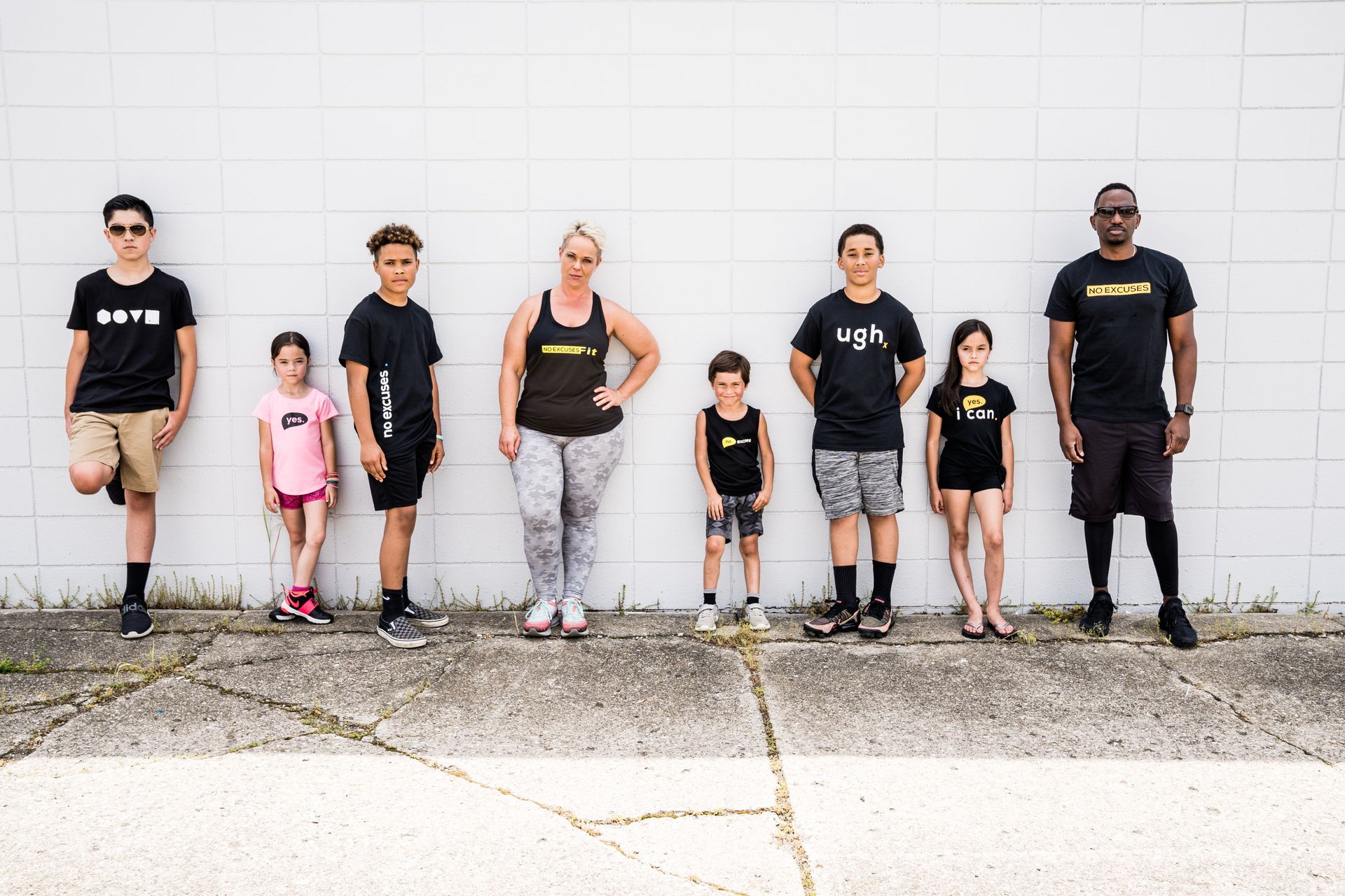 A group of people are standing in front of a white brick wall.