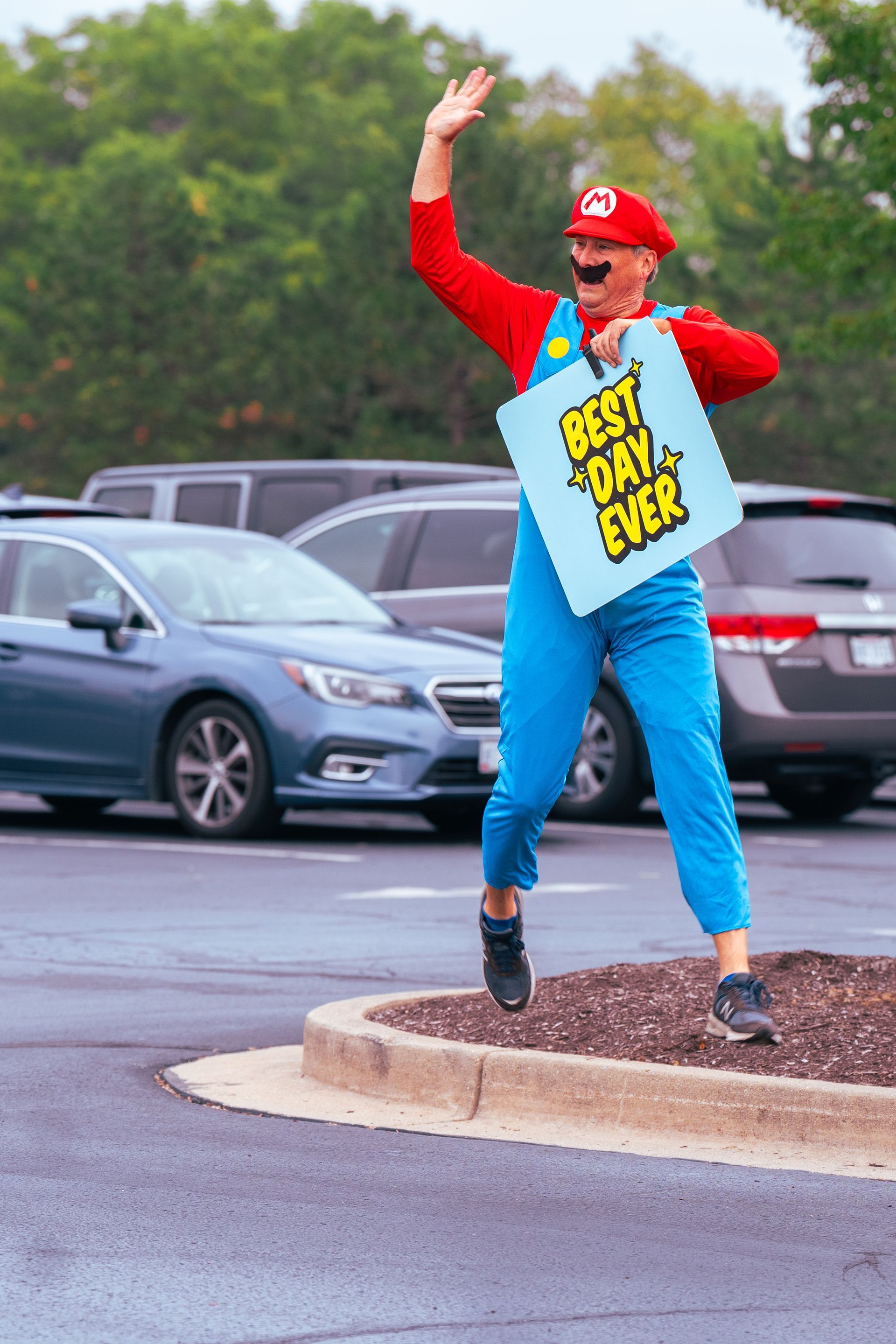 A man in a mario costume is holding a sign that says best day ever