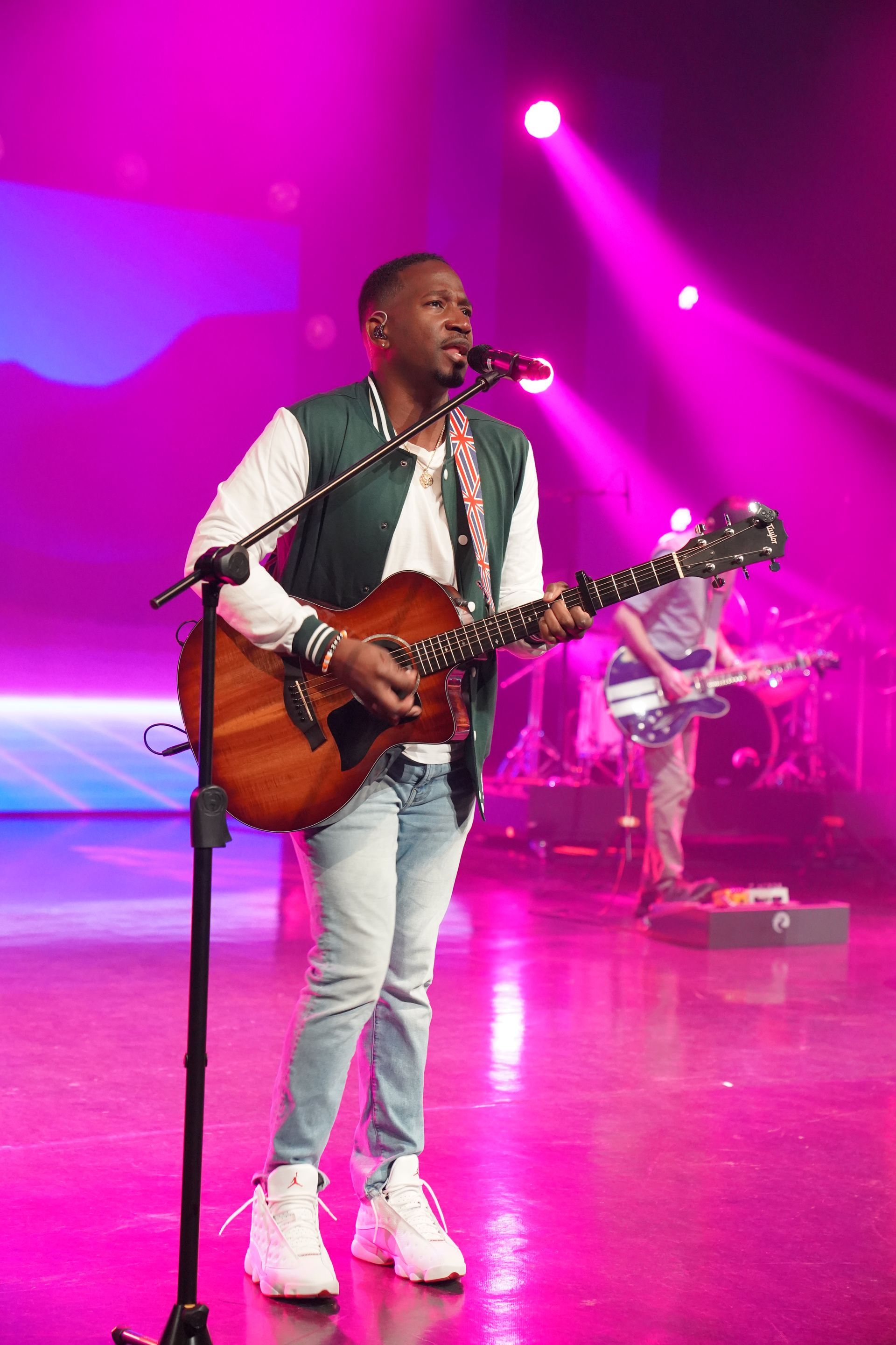 A man is playing a guitar and singing into a microphone on a stage.