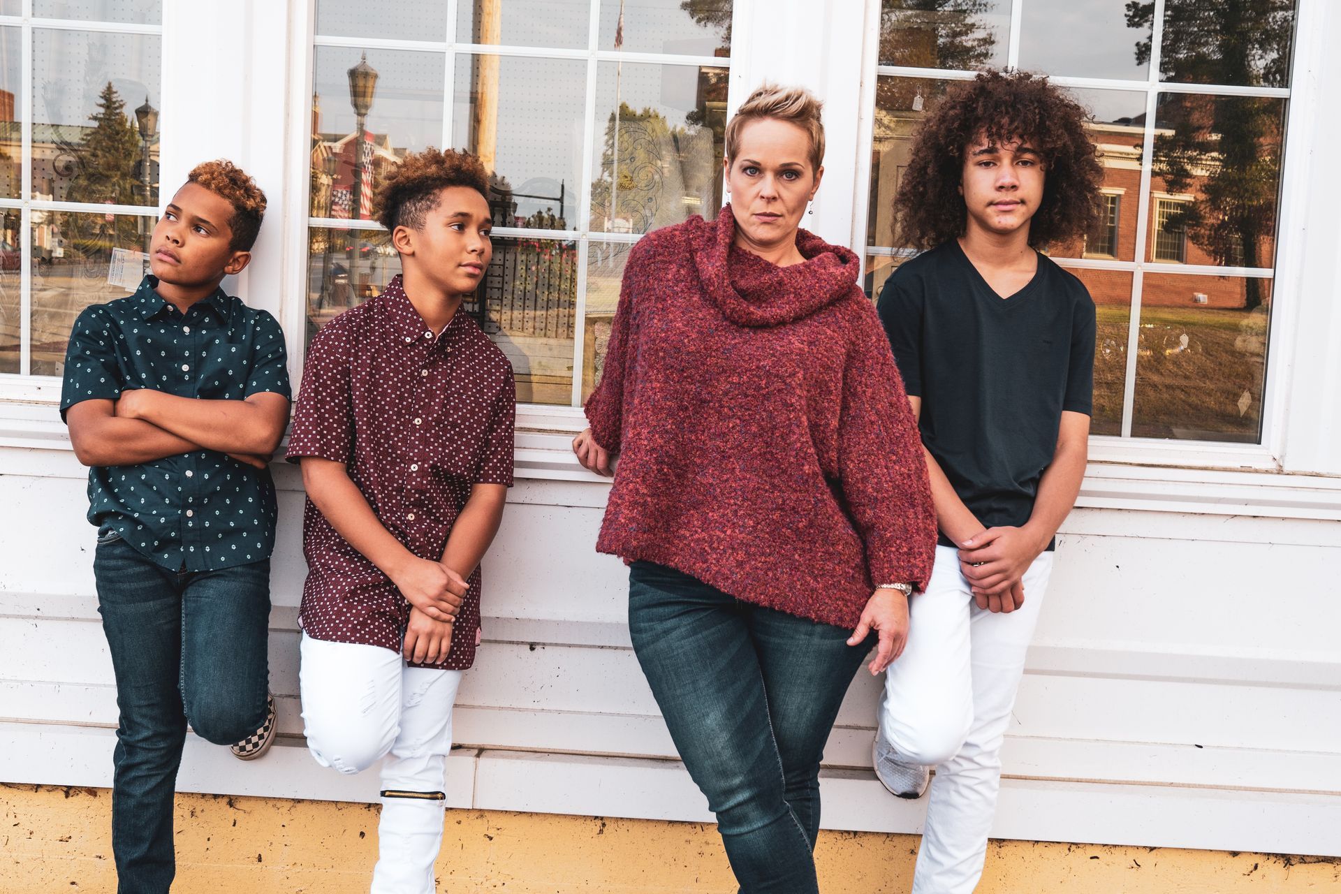 A woman and three children are standing in front of a window.