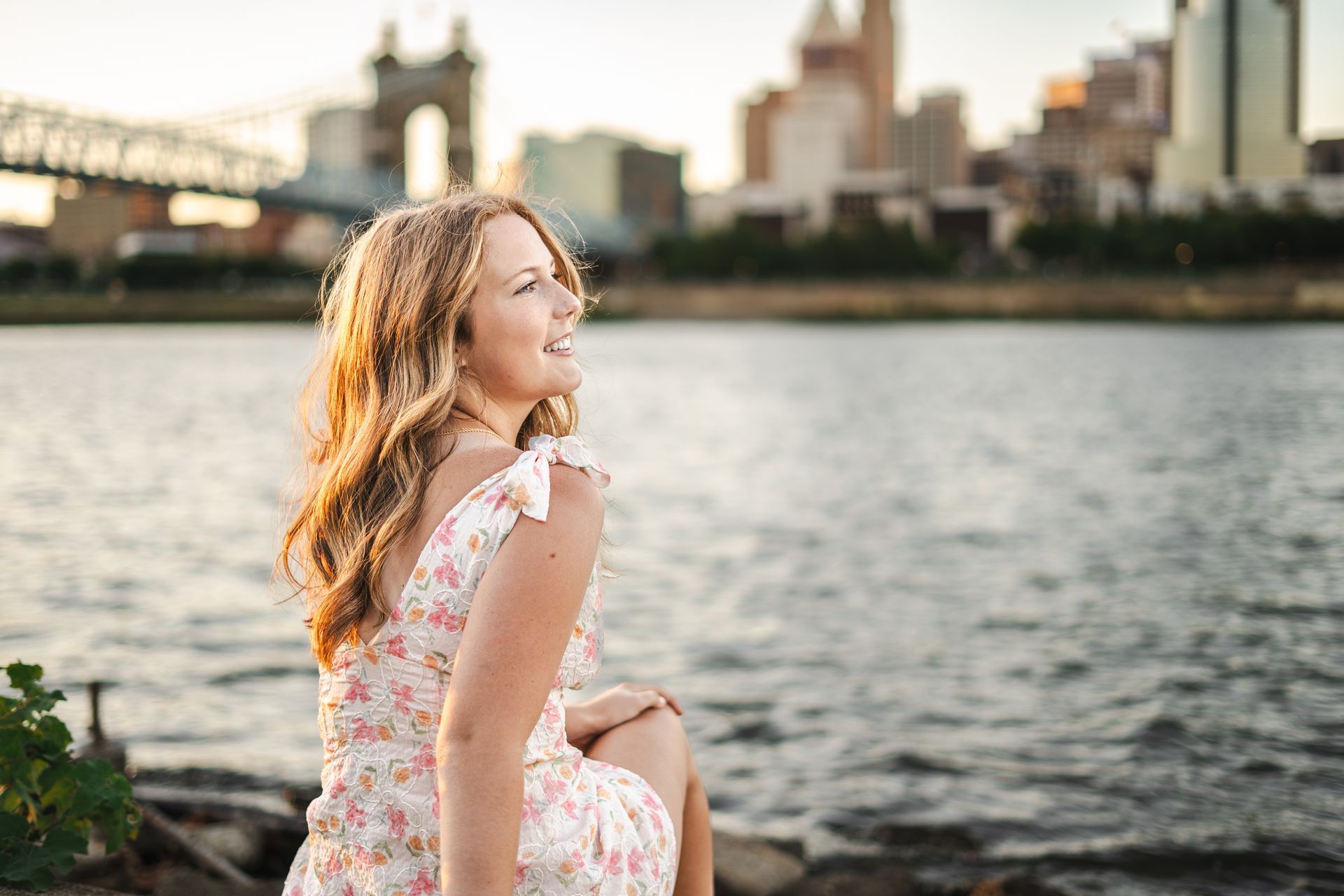 A woman in a white dress is sitting on the shore of a body of water.