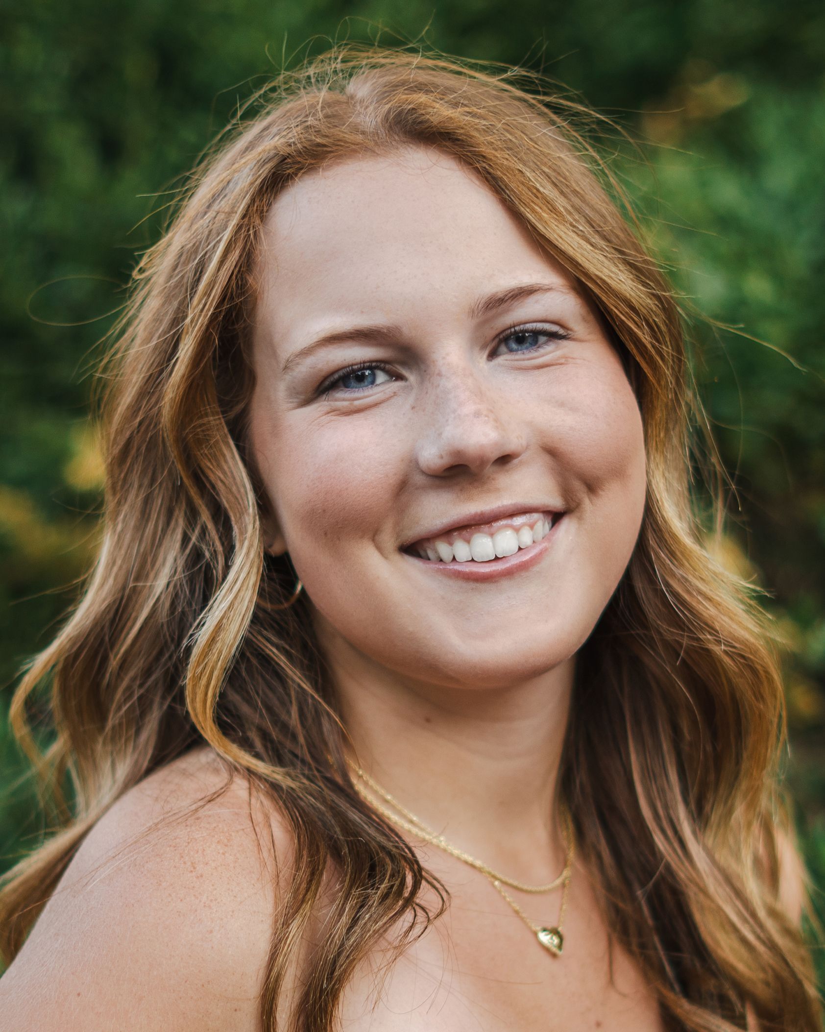 A close up of a woman wearing a necklace and smiling.