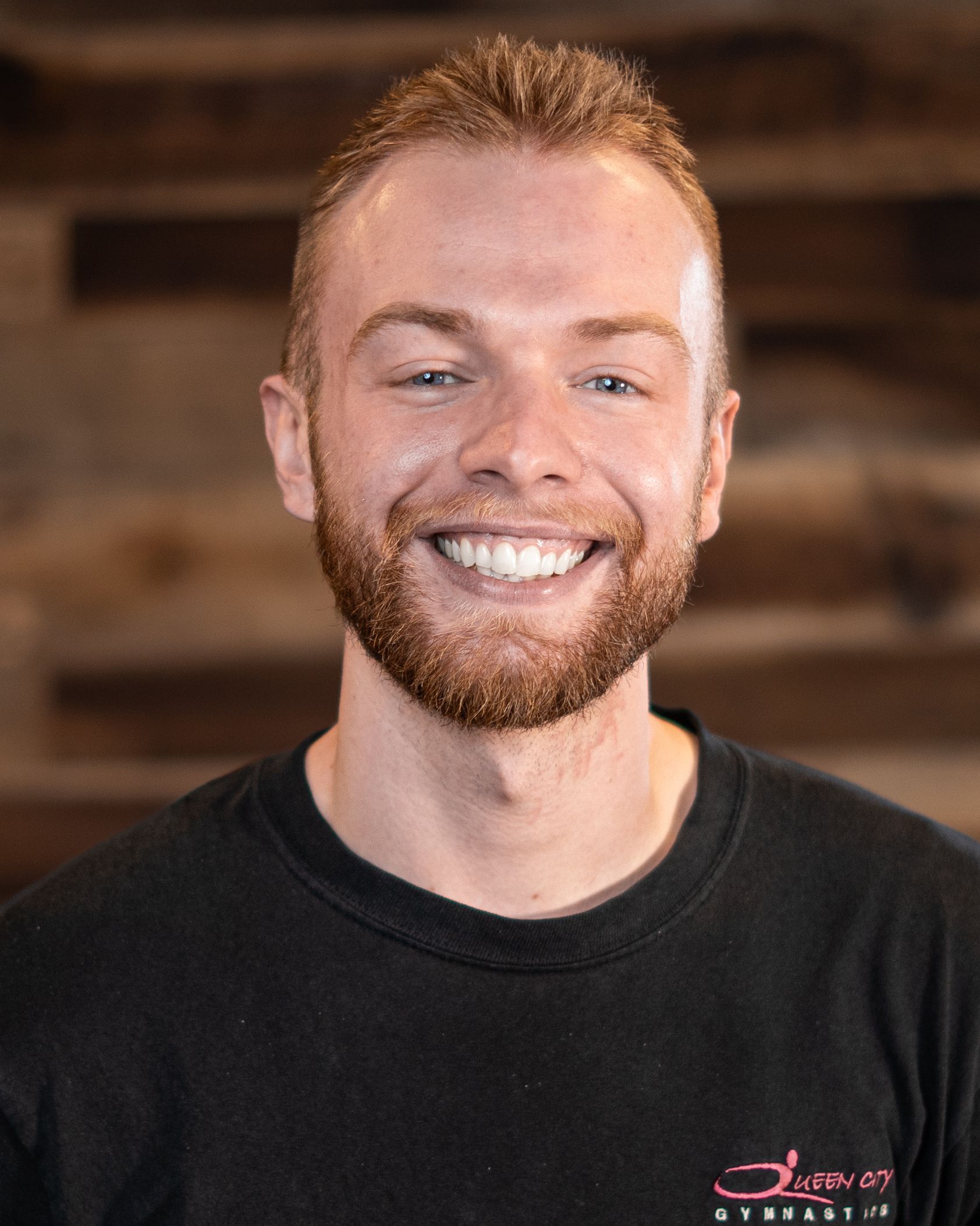 A man with a beard is smiling and wearing a black shirt.