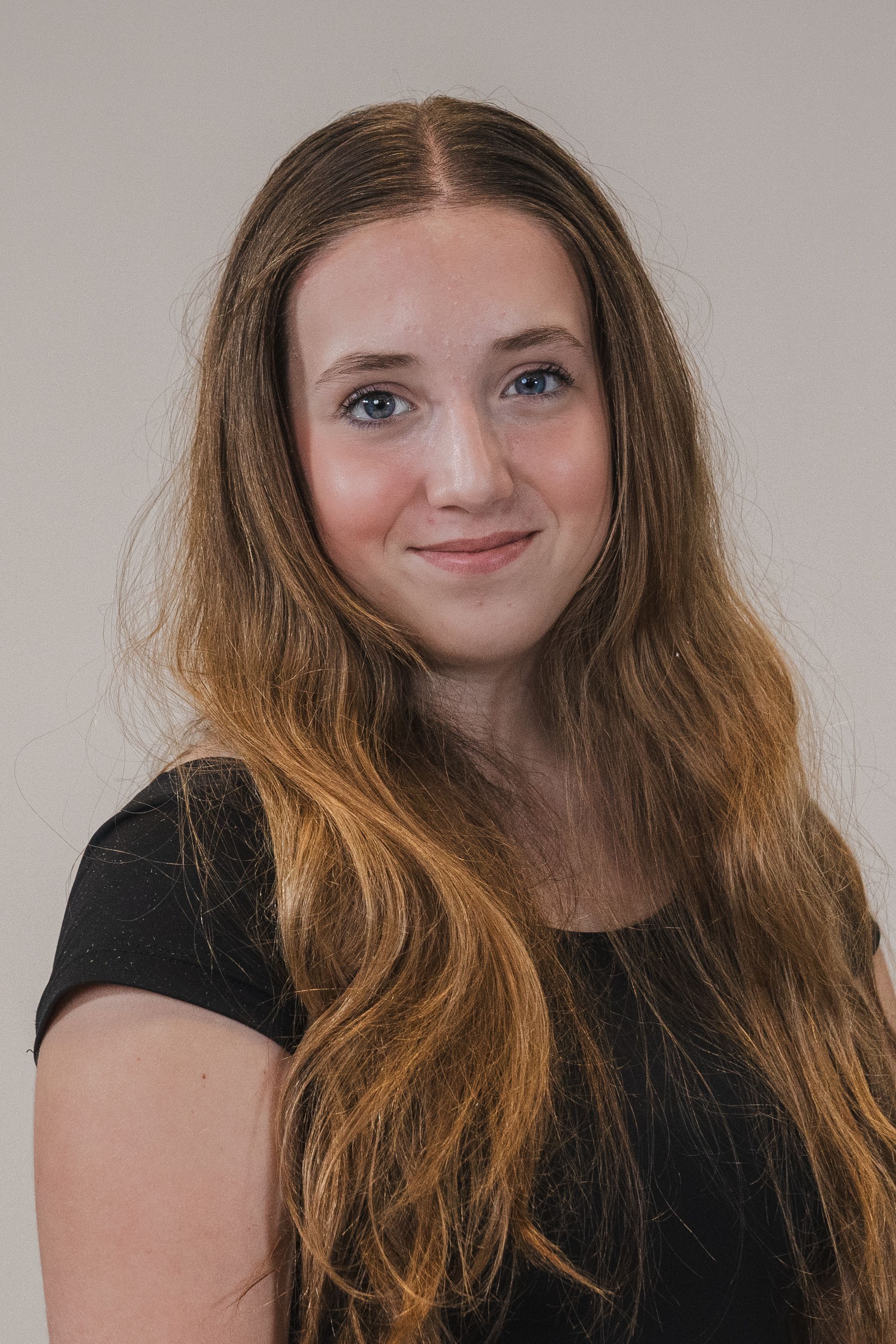 A young woman with long hair is wearing a black shirt and smiling.