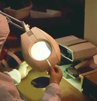 A person is holding a magnifying glass in front of a lamp.