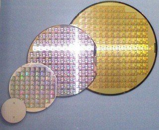 Three different sized semiconductor wafers are lined up on a table