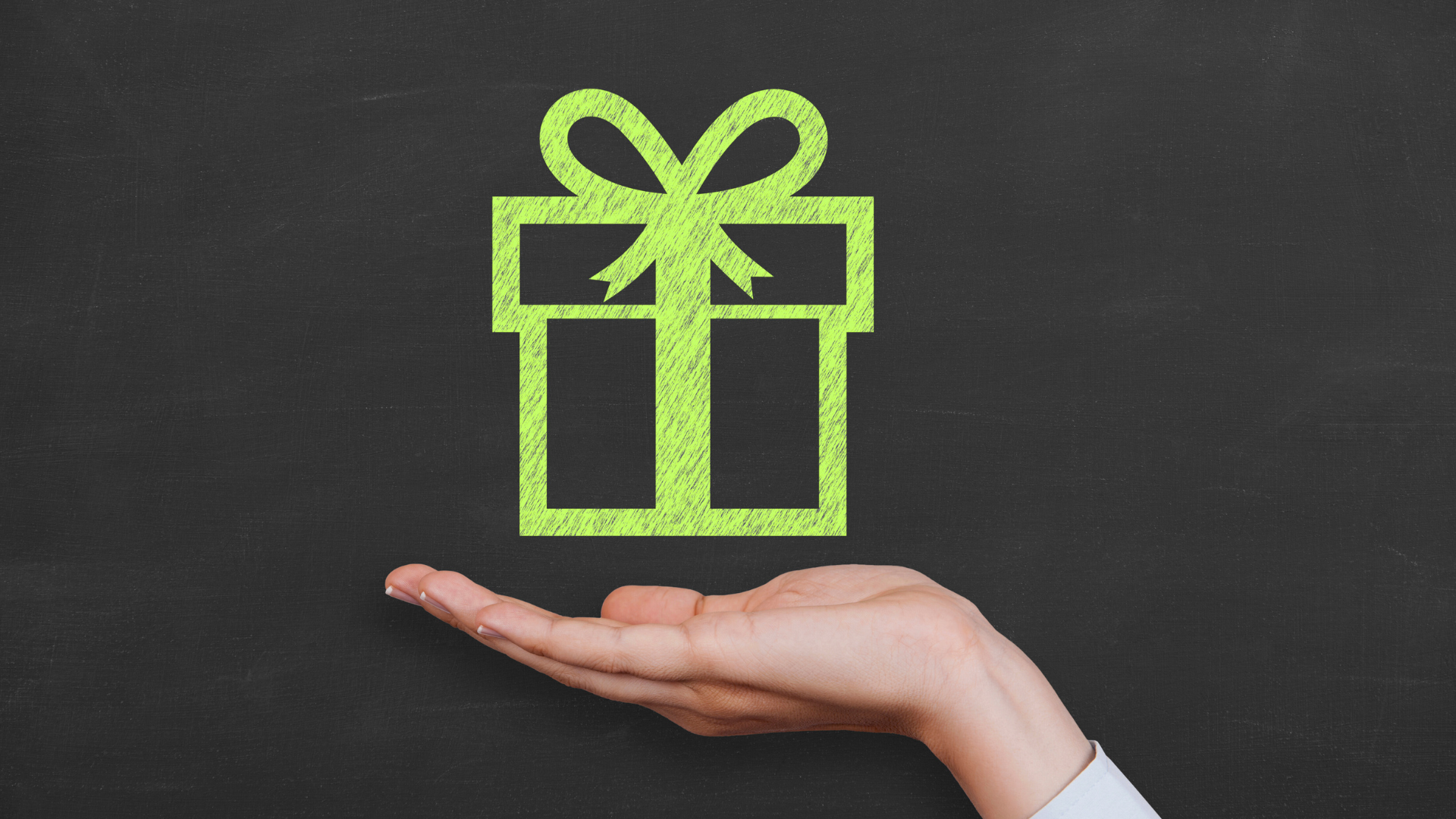 Tan church building with a cross, under large tree, gravel path.