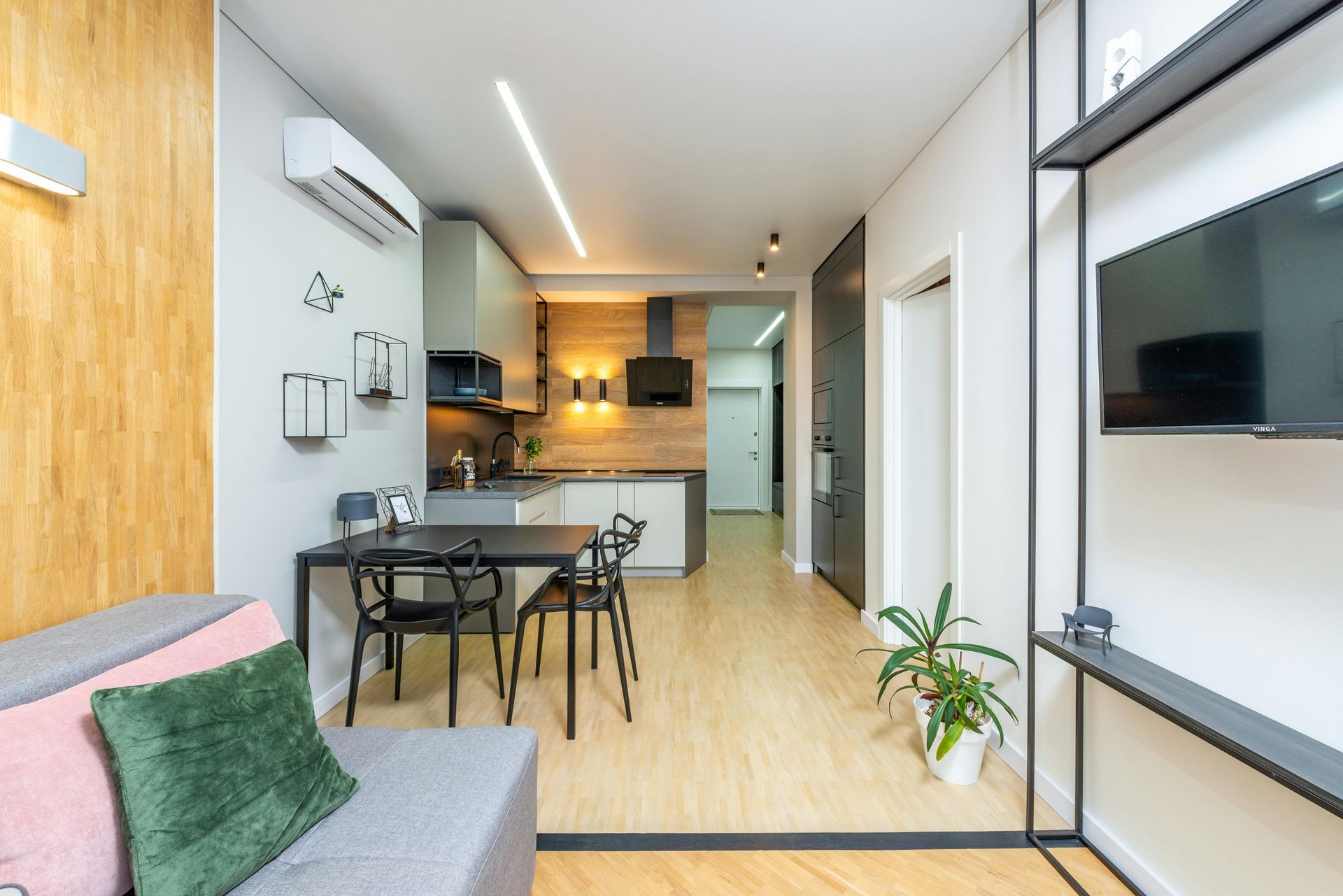 A living room with a couch , table and chairs and a flat screen tv.