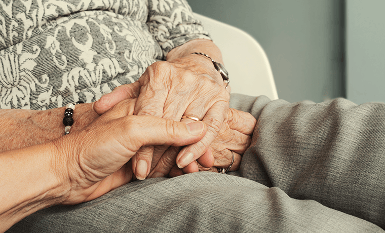 An elderly woman holding hands with her daughter.