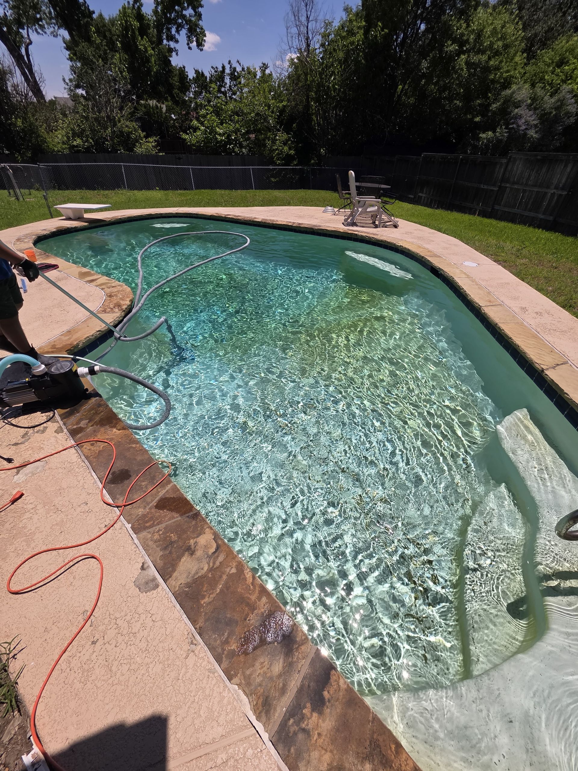 A person using a handheld vacuum cleaner to clean a mattress surface.