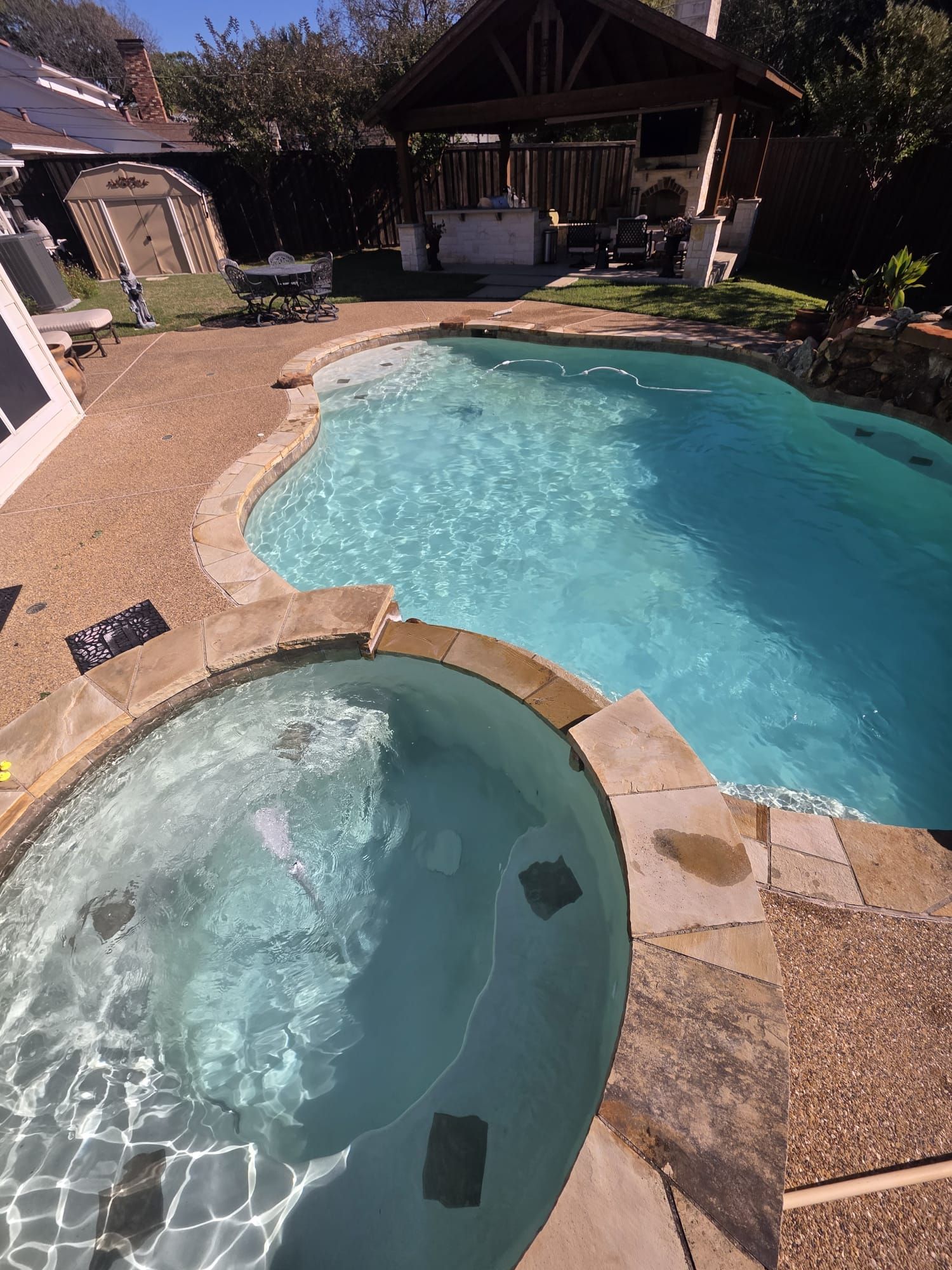 A person using a handheld vacuum cleaner to clean a mattress surface.