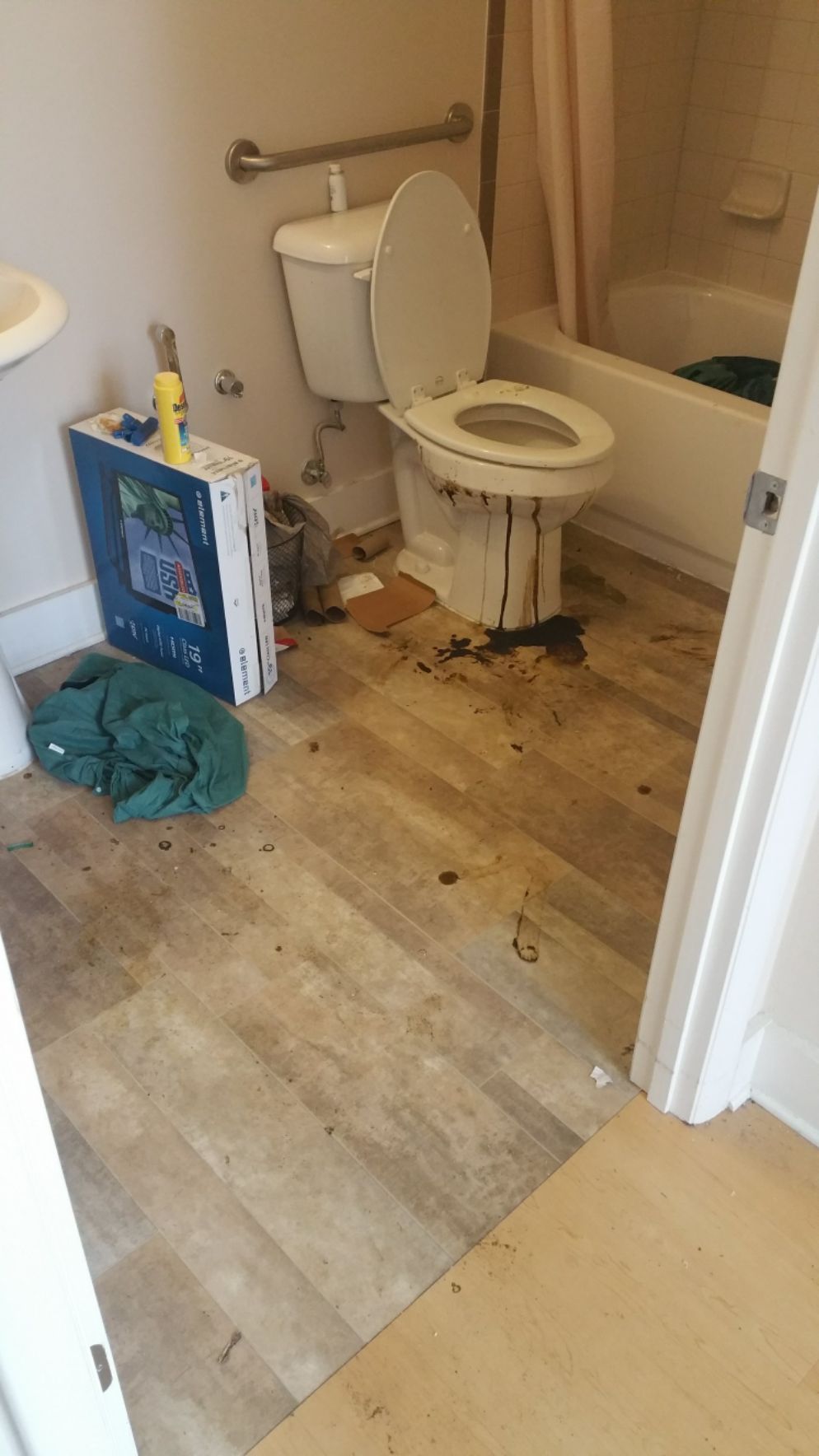 Bathroom with a toilet covered in dark stains, debris on floor.