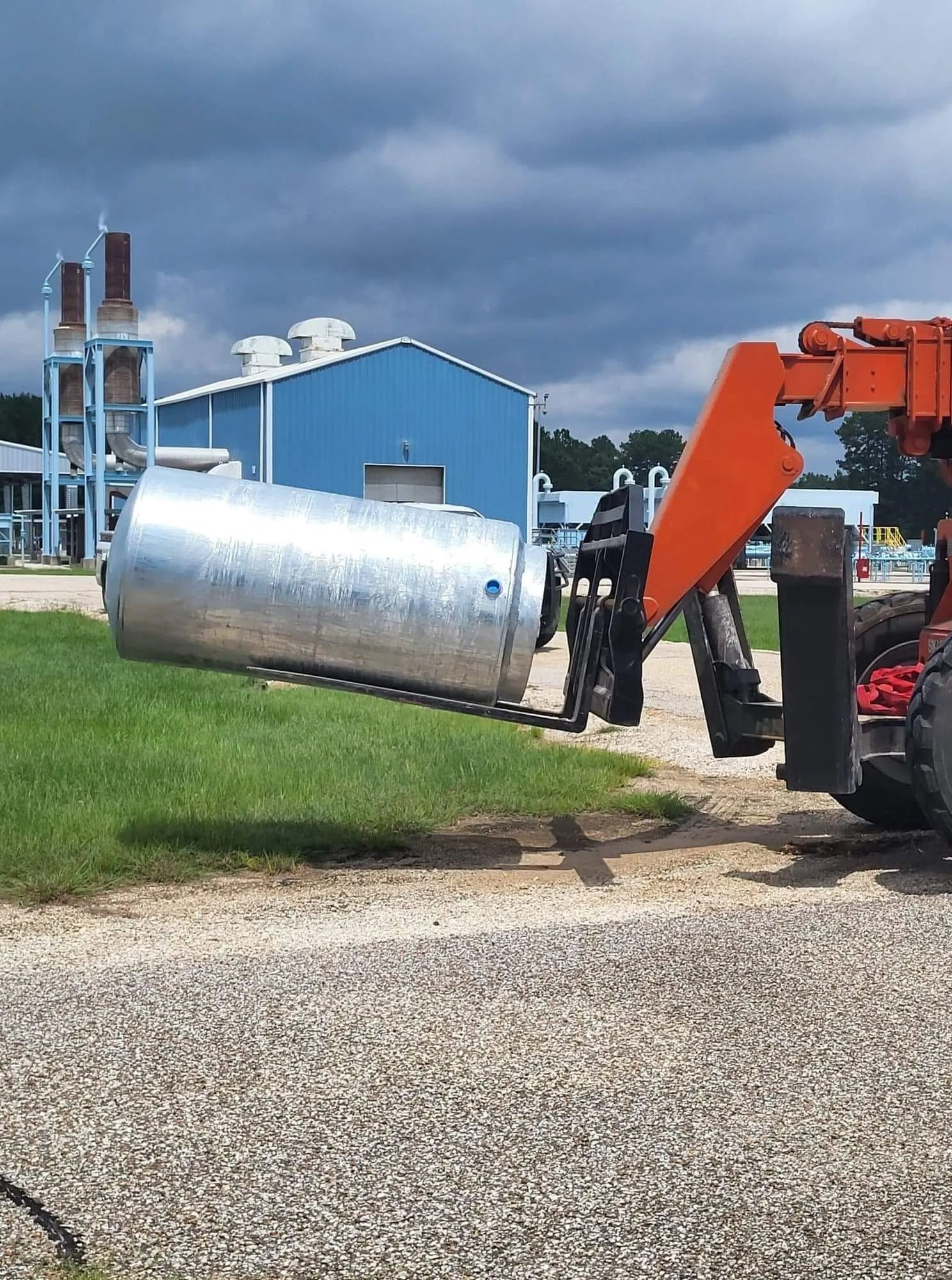 A large metal tank is being lifted by a forklift