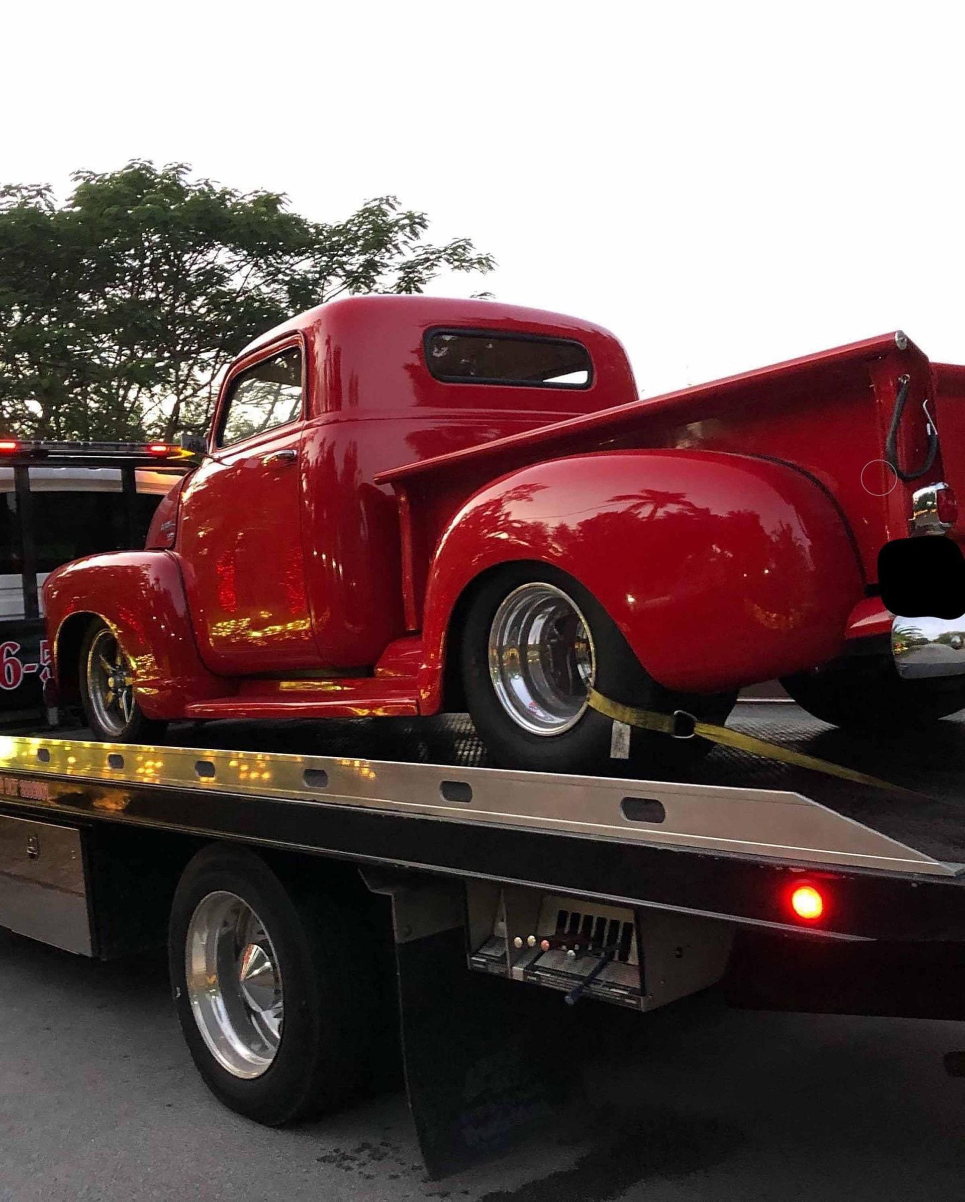 Red classic truck on a flatbed tow truck. Shiny paint, chrome wheels.