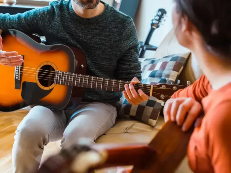 Image of a person learning guitar lessons from a teacher.