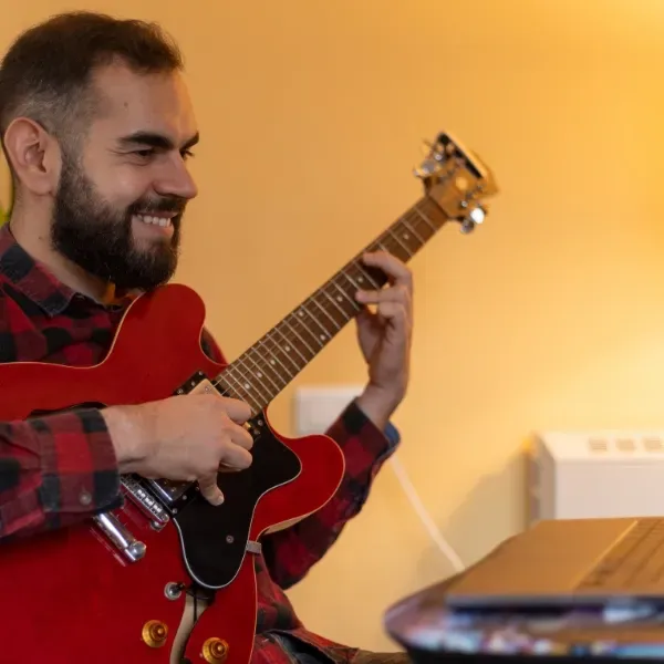 Image of a person learning guitar online. 
