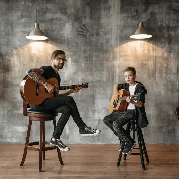 Image of a person learning guitar with a teacher.