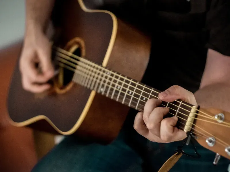 Image of a person playing guitar with the right hand.
