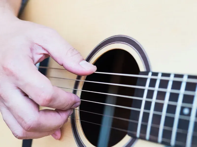 Image of a person strumming guitar strings.