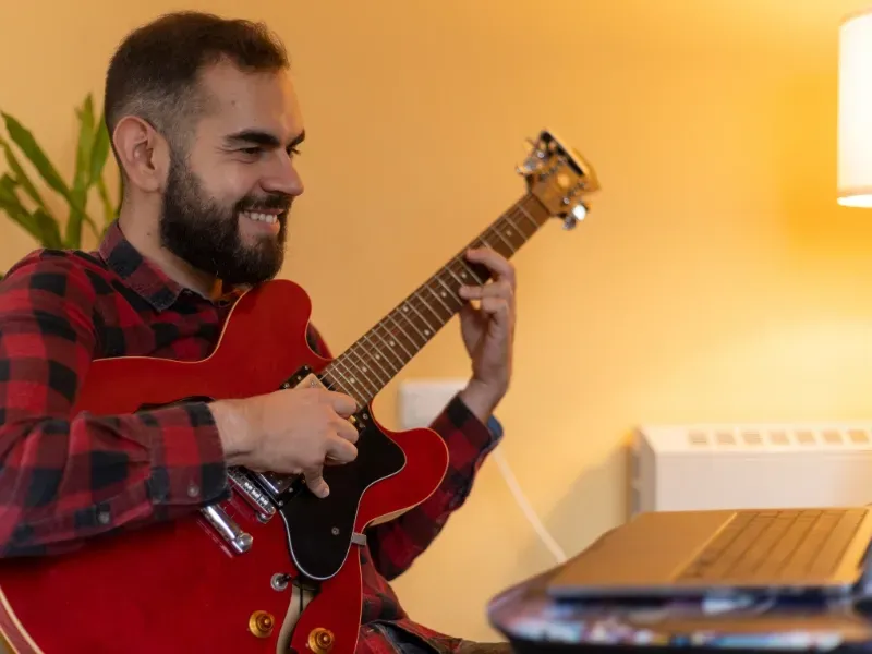 Image showing a teacher with a student learning guitar online.