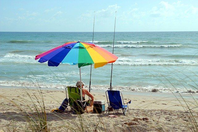 sitting on beach under a rainbow colored umbrella