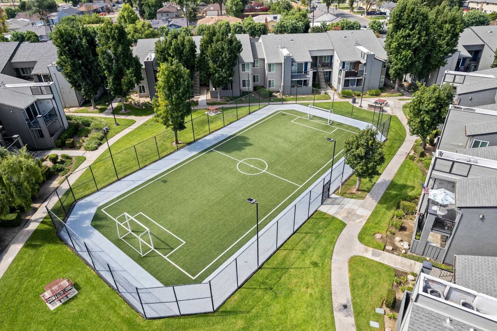 An aerial view of a soccer field in a park surrounded by buildings.