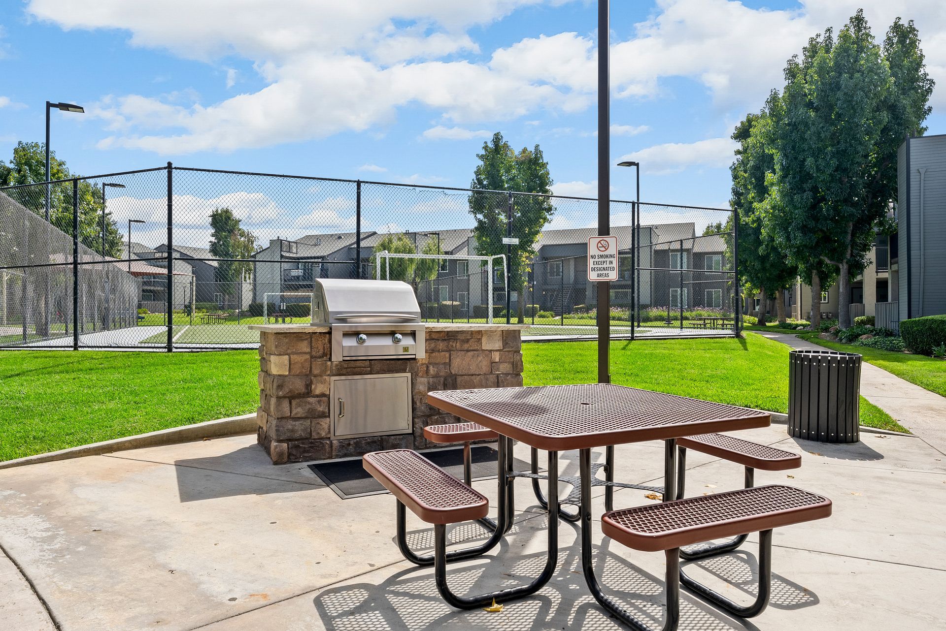 A picnic table with benches and a grill in a park.