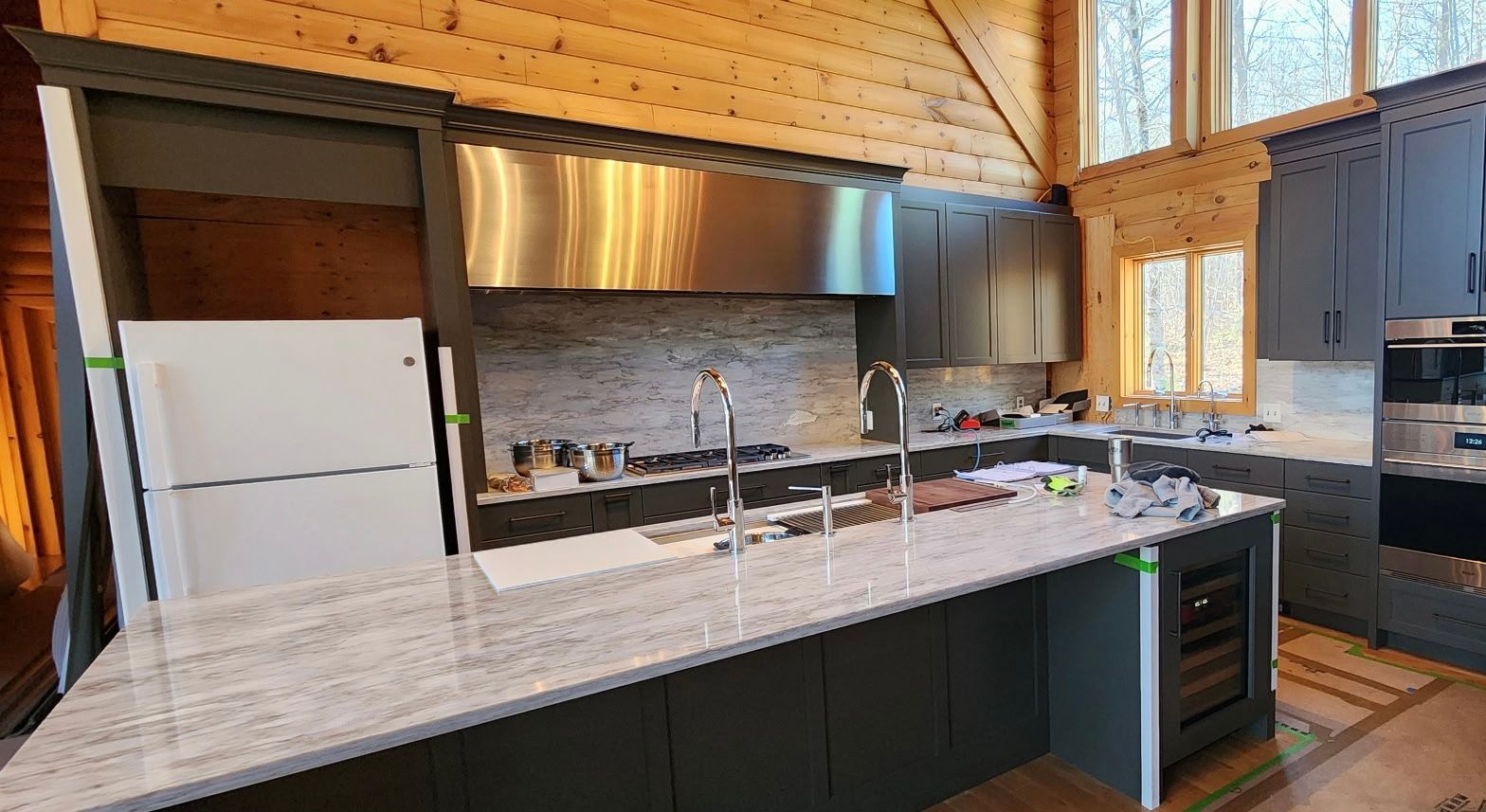 Modern kitchen with gray cabinets, stainless steel appliances, and a marble countertop.