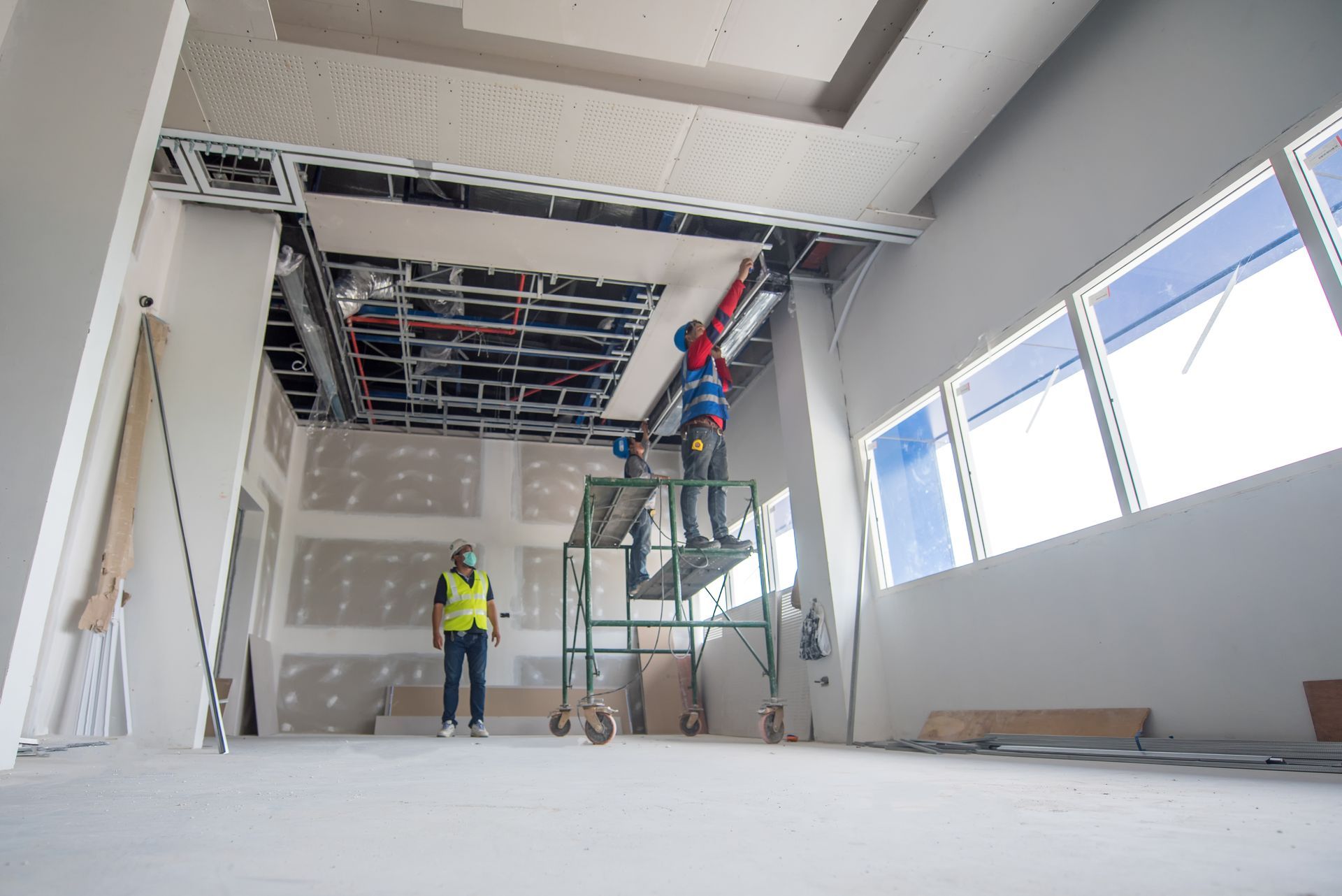 Un homme se tient debout sur un échafaudage dans une pièce en construction.