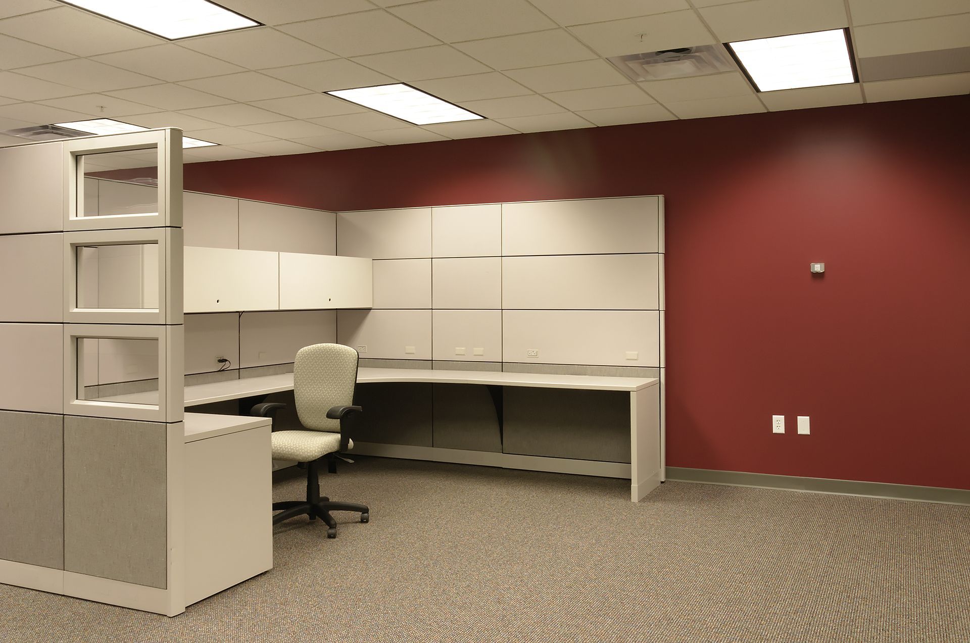 Une cabine dans un bureau avec un mur rouge