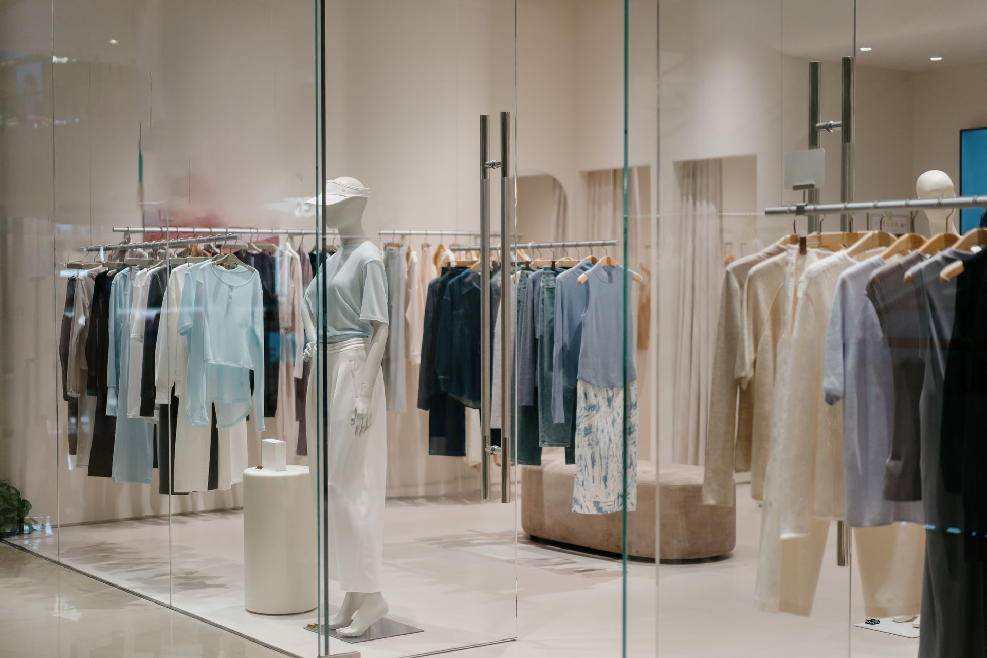 Un magasin de vêtements avec un mannequin devant une porte vitrée.