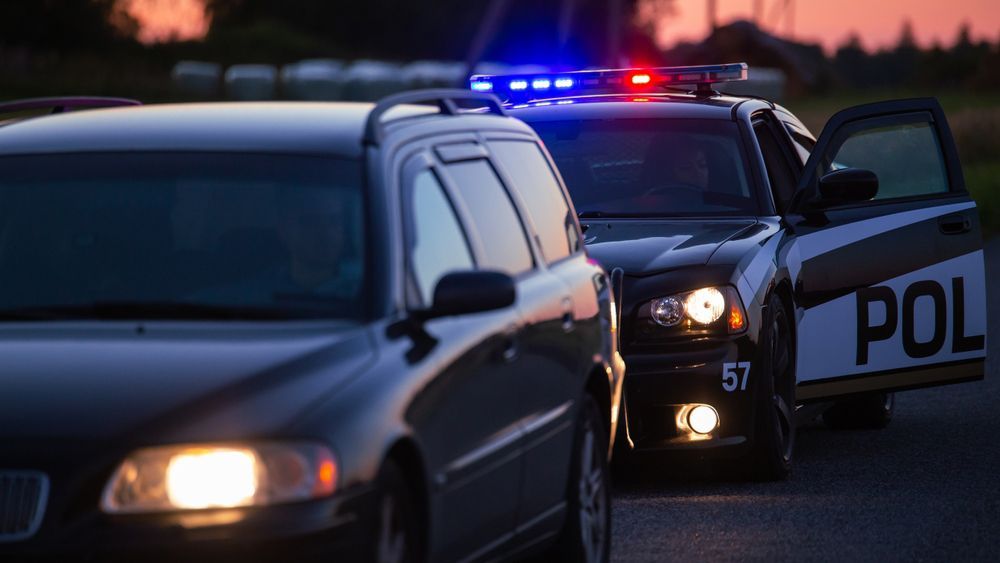 A car and a police car are parked next to each other on the side of the road.