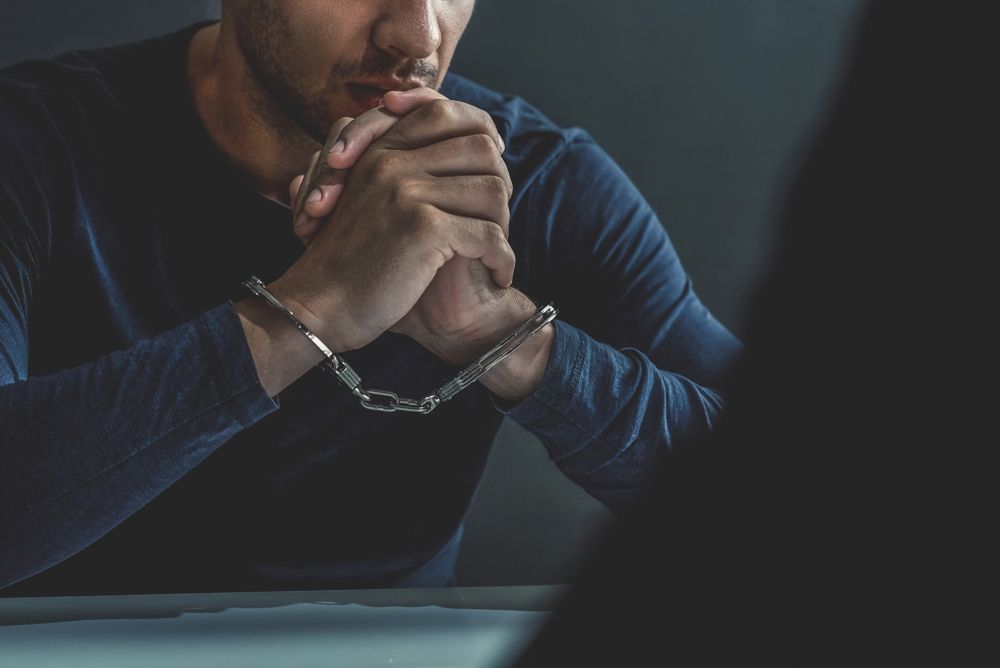 A man in handcuffs is sitting at a table.