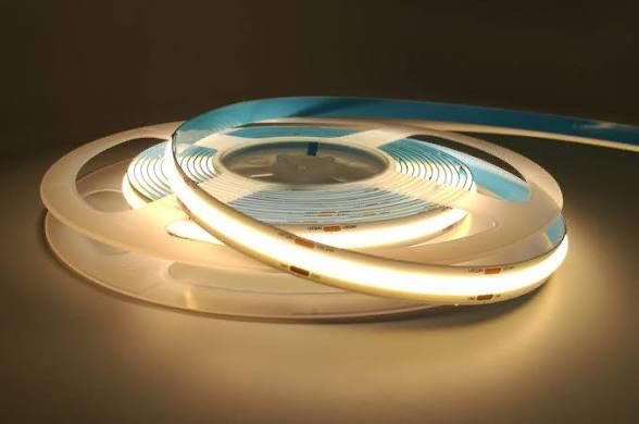 Spool of flexible LED strip light emitting warm white light.